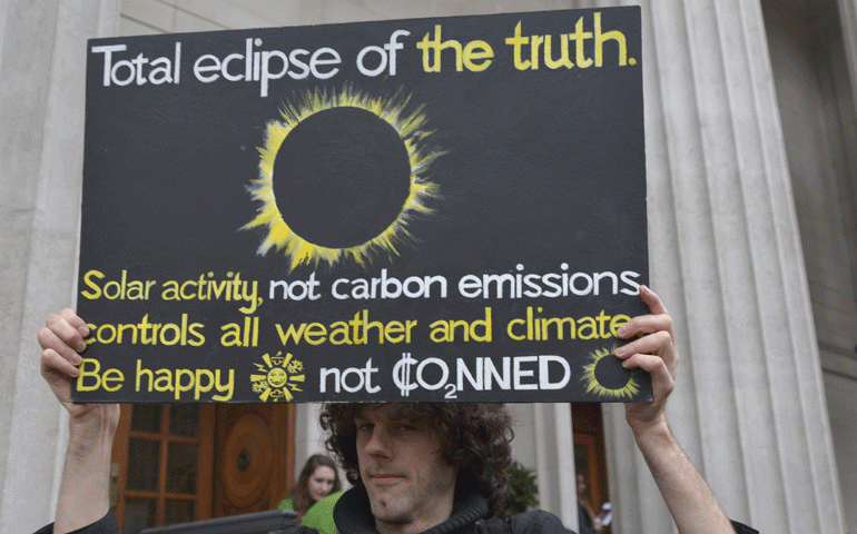 A man protests outside a climate change event in London. (National Catholic Reporter)