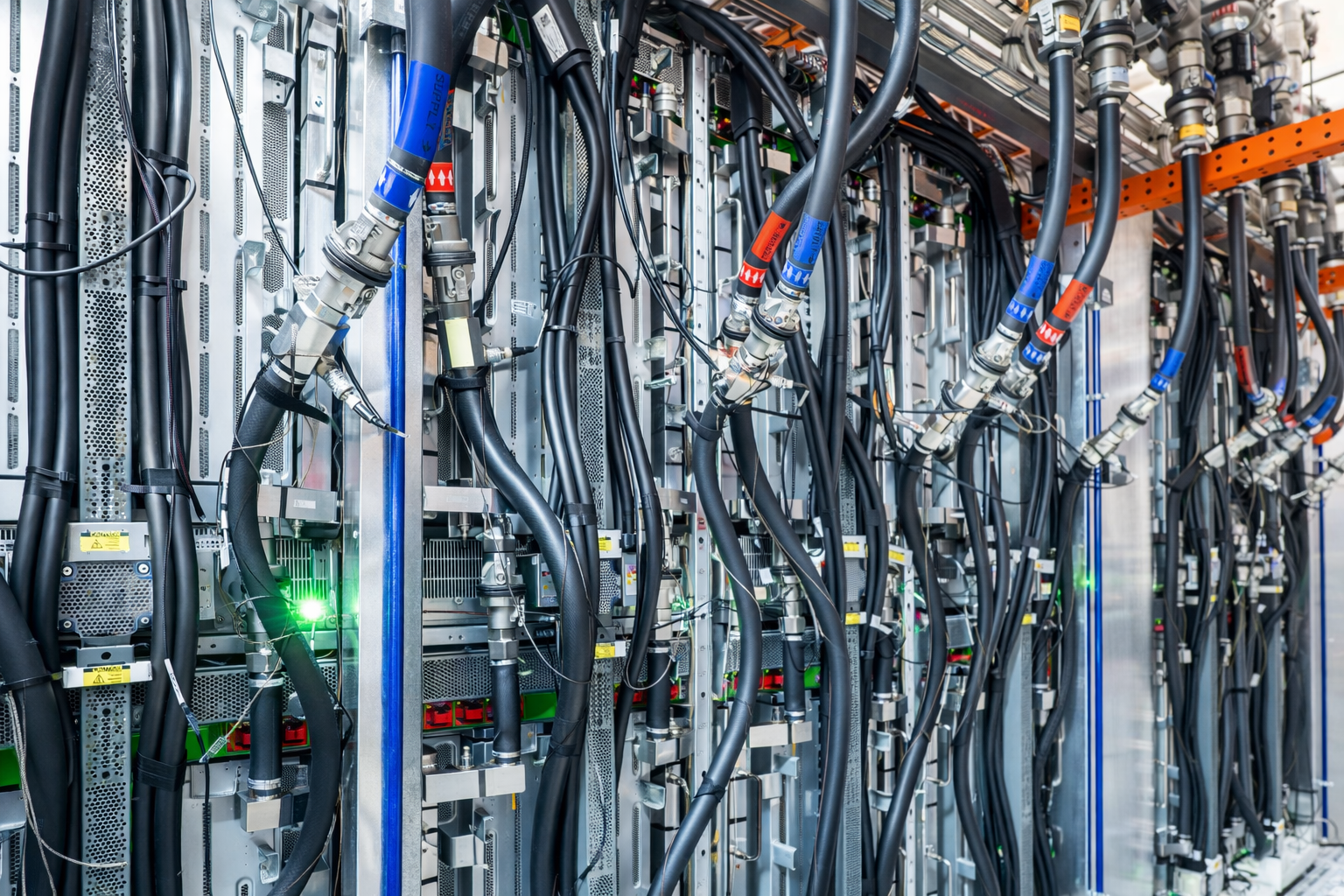 Close-up of a data center server rack with numerous black cables connected to hardware components, some with colored labels and indicators.
