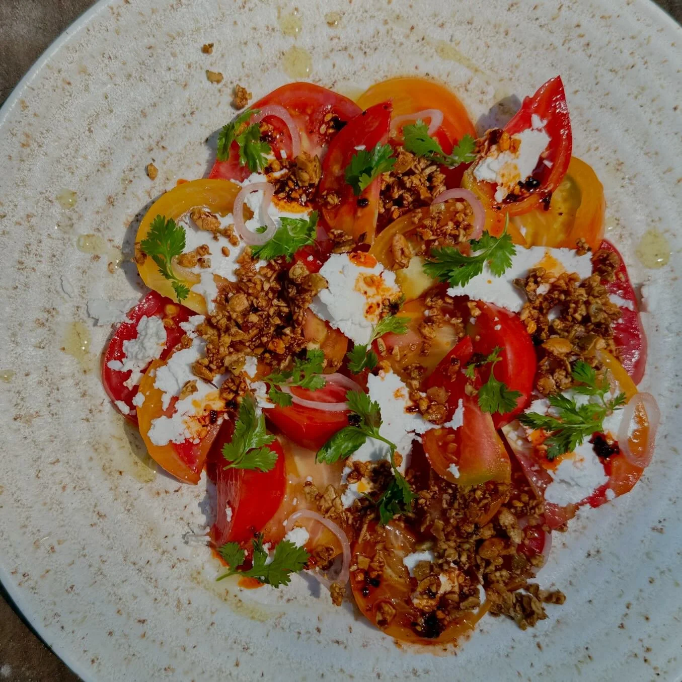Impatiently waited all year to make a salad like this. The sweetest, juiciest heirloom tomatoes with pickled shallot, toasted garlic &amp; pepita crumble (the crunch factor is 💯), shaved cotija, smoky chili oil and cilantro.