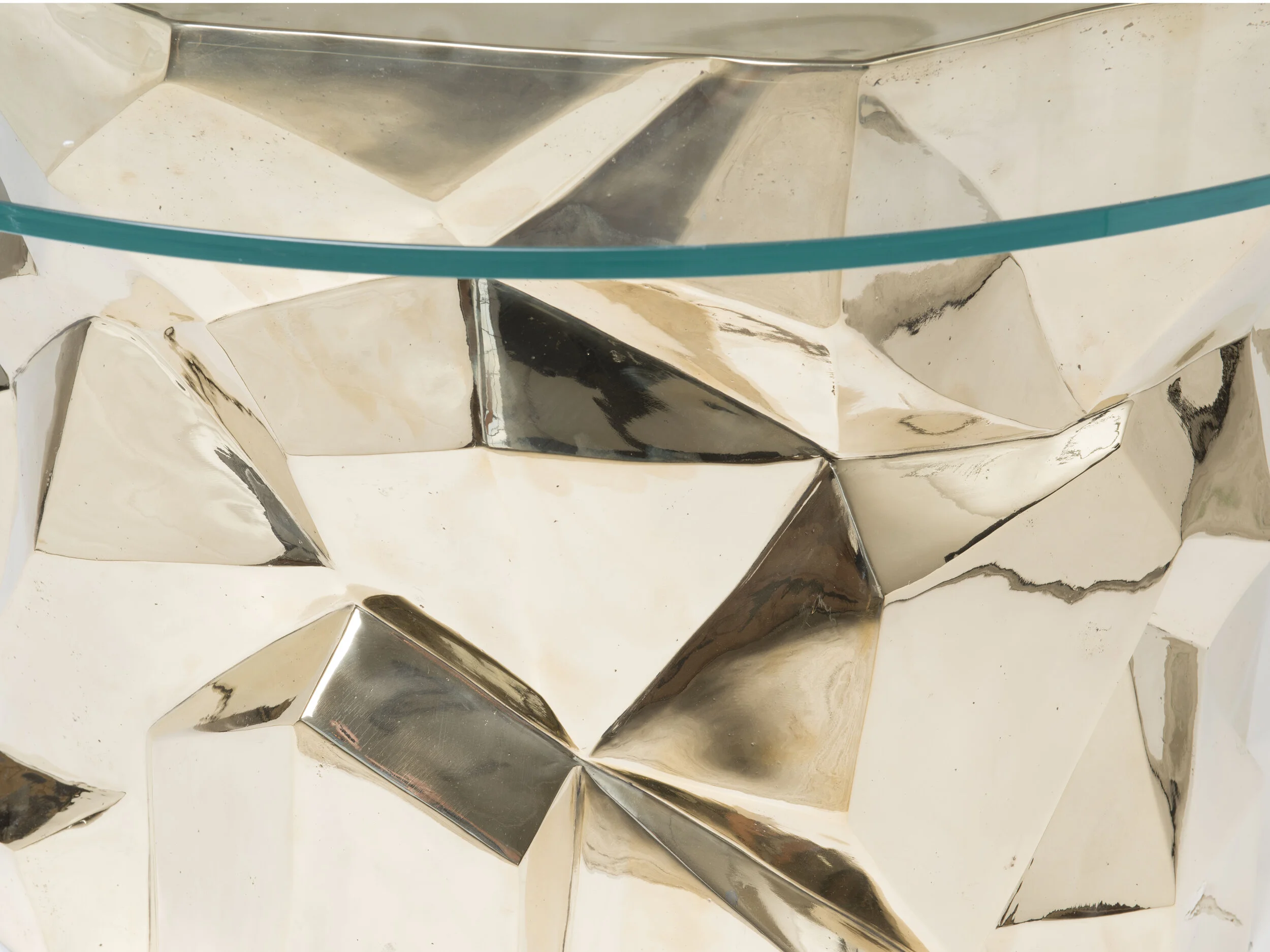 Detail view of the Facet Dining Table with round glass top and faceted bronze base