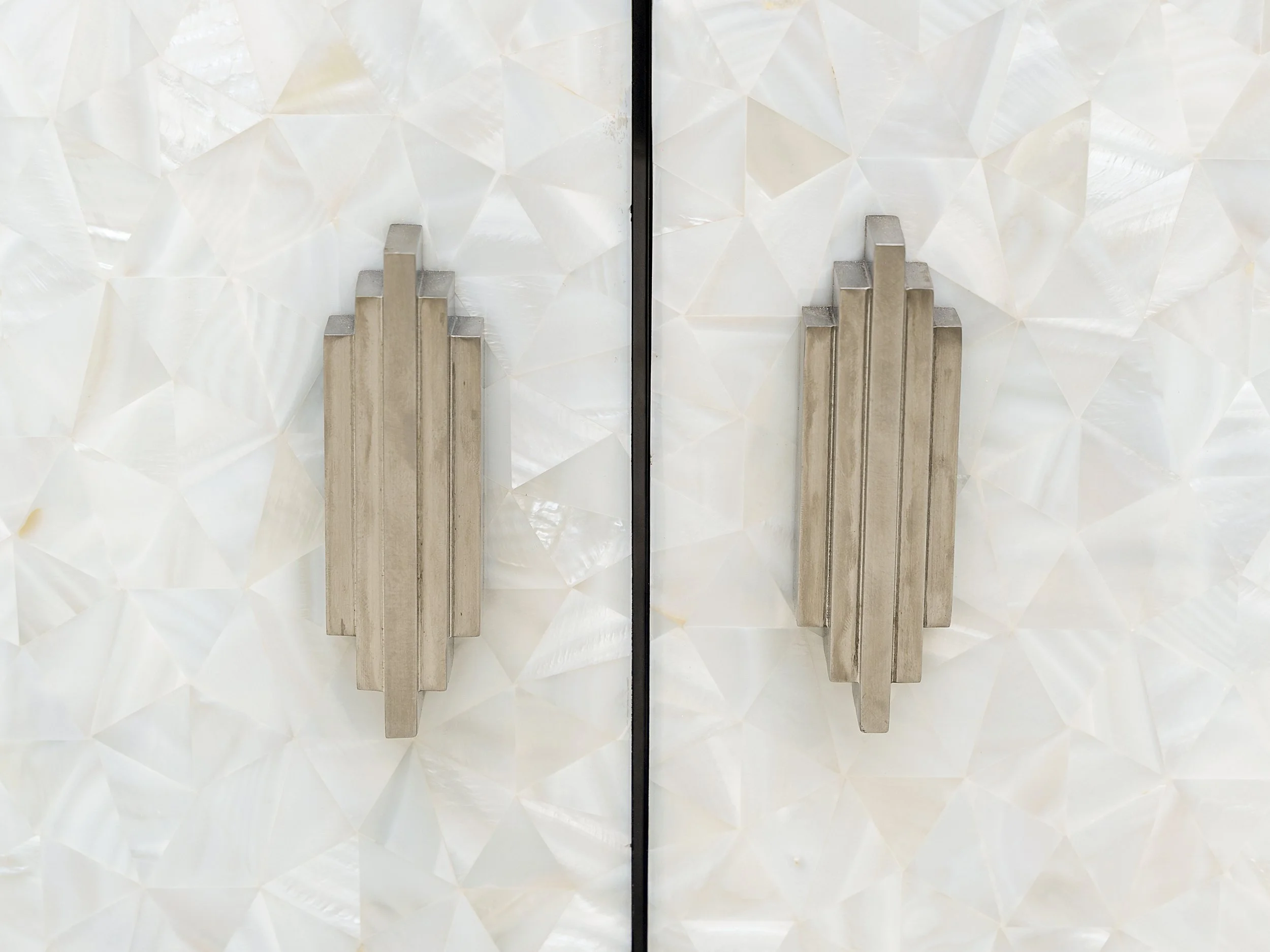 Close-up of bronze 'Century' handles on white mother-of-pearl cabinet doors