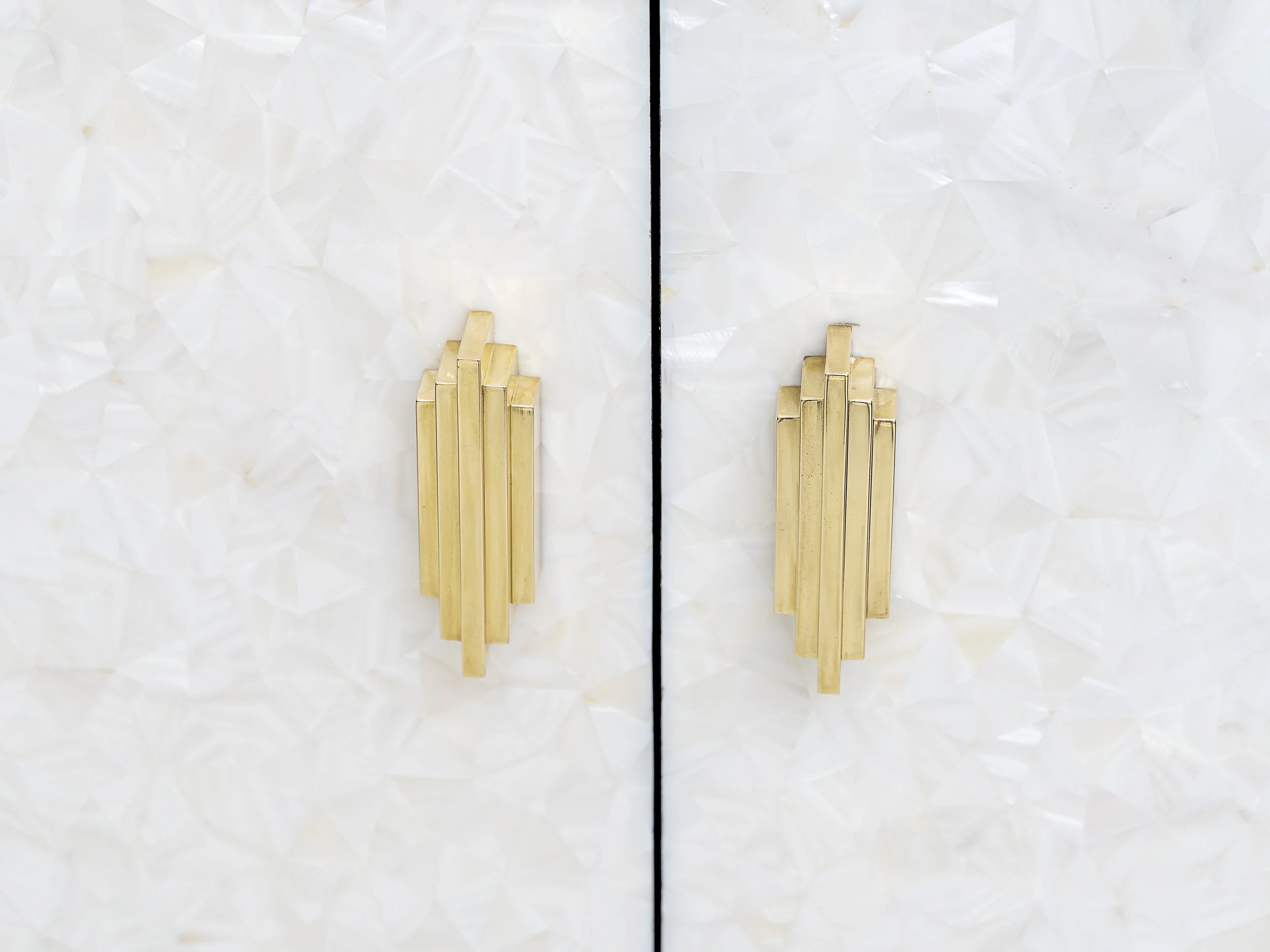 Close-up of bronze 'Century' handles on white mother-of-pearl cabinet doors