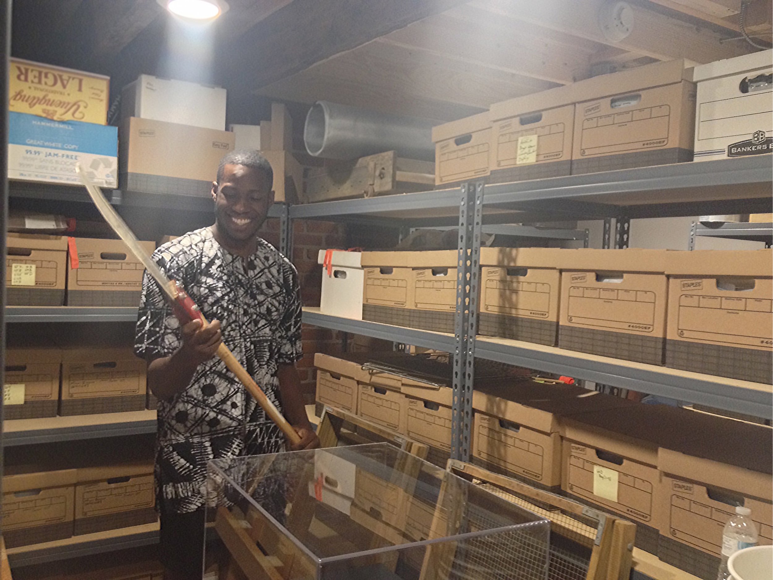 PCE Intern Isaac Udogwu holding archived farming tool.