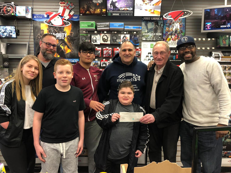 Michael Capolongo, the namesake of Michael’s Cause, receives a check from Murray Berman, second from right, owner of South Shore Commons