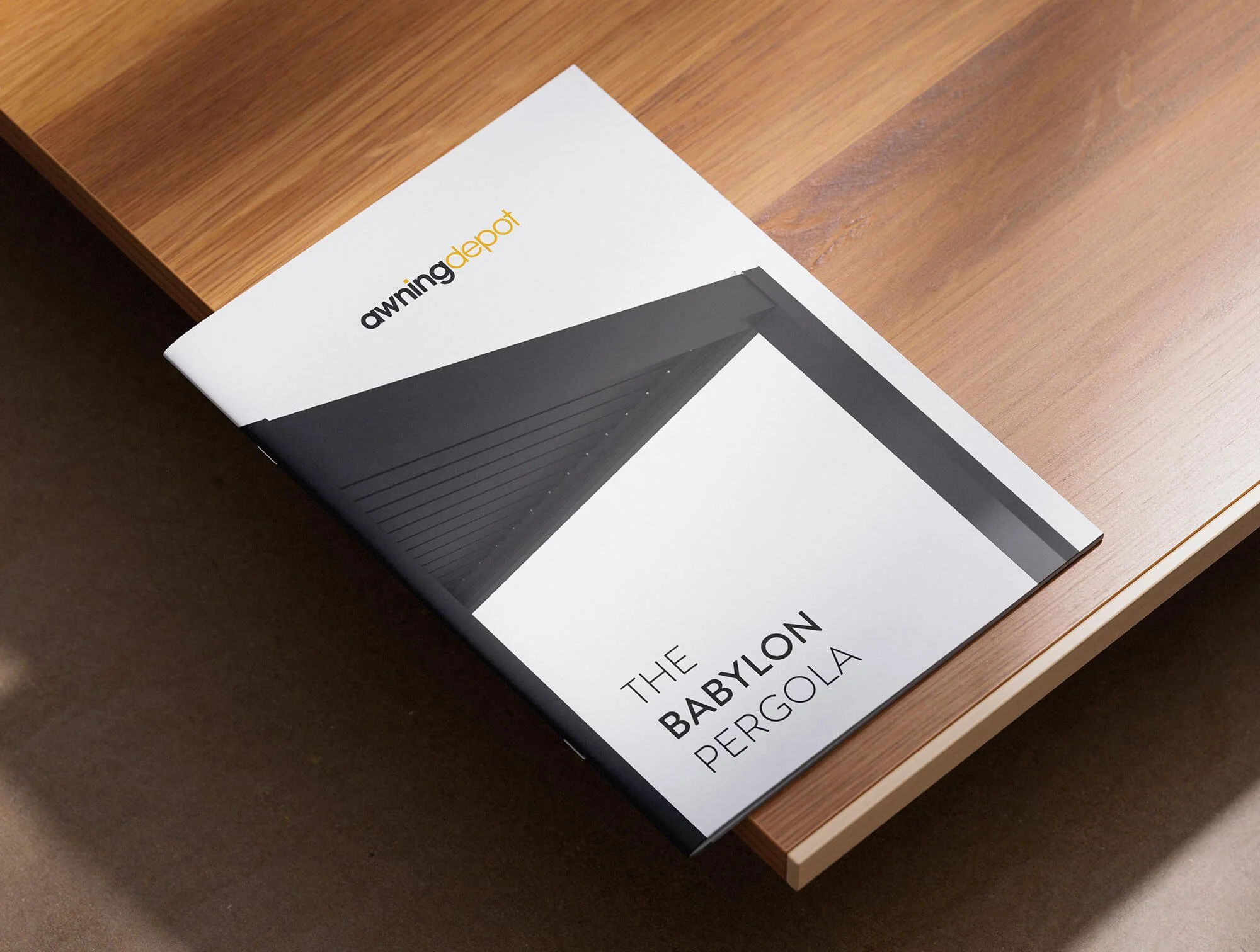 A brochure titled "The Babylon Pergola" from "awning depot" on a wooden table.