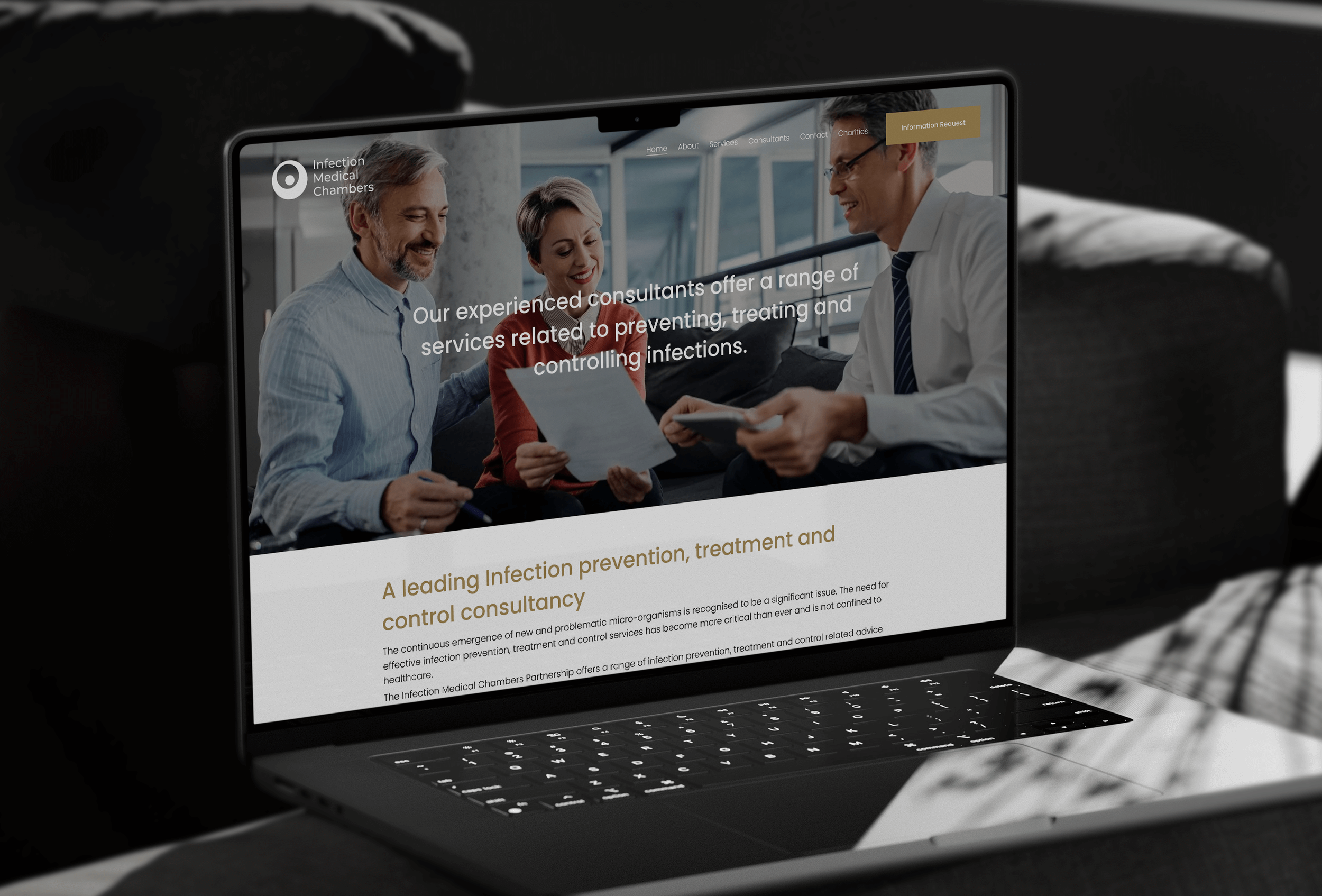 Laptop displaying a healthcare website with a photo of three people in a medical setting, sitting and discussing documents.