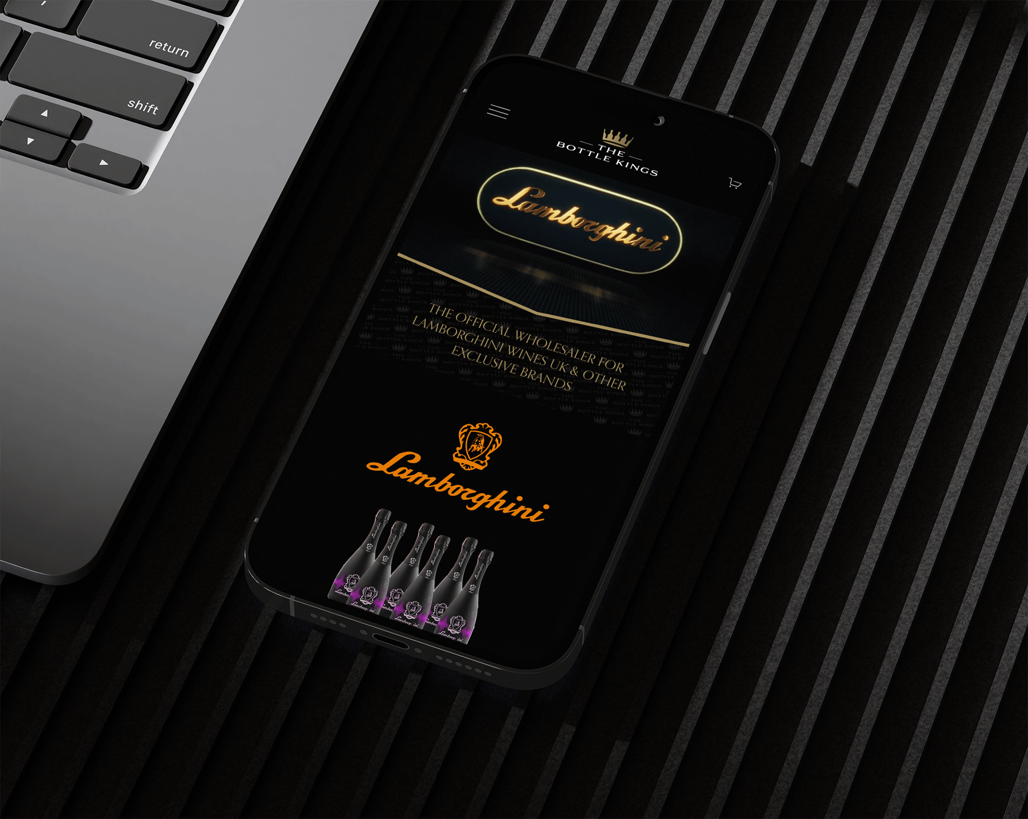 Smartphone displaying the Lamborghini official wholesaler website, showing a logo, some wine bottles, and a black background, placed on a black slatted surface next to a laptop.