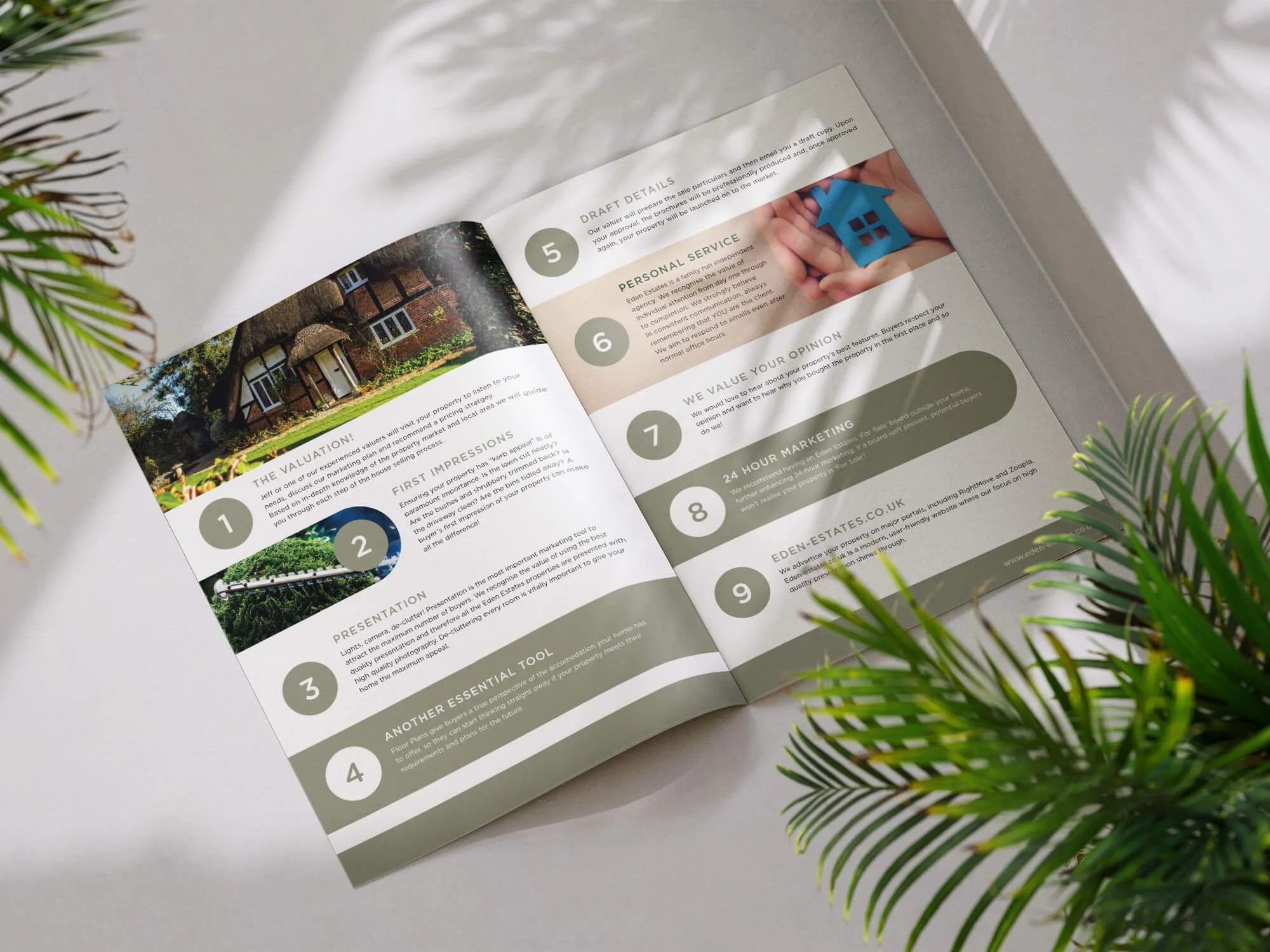 Open real estate brochure on a white surface surrounded by green plants. The brochure features images of a house, garden, and colorful property details, including sections on valuation, impressions, tools, and marketing.