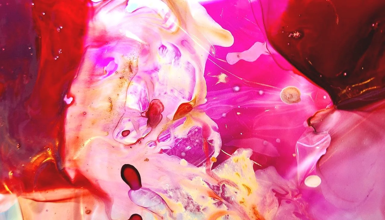 Abstract ocean scene with pink, purple, red, and yellow swirling colors and bubbles.