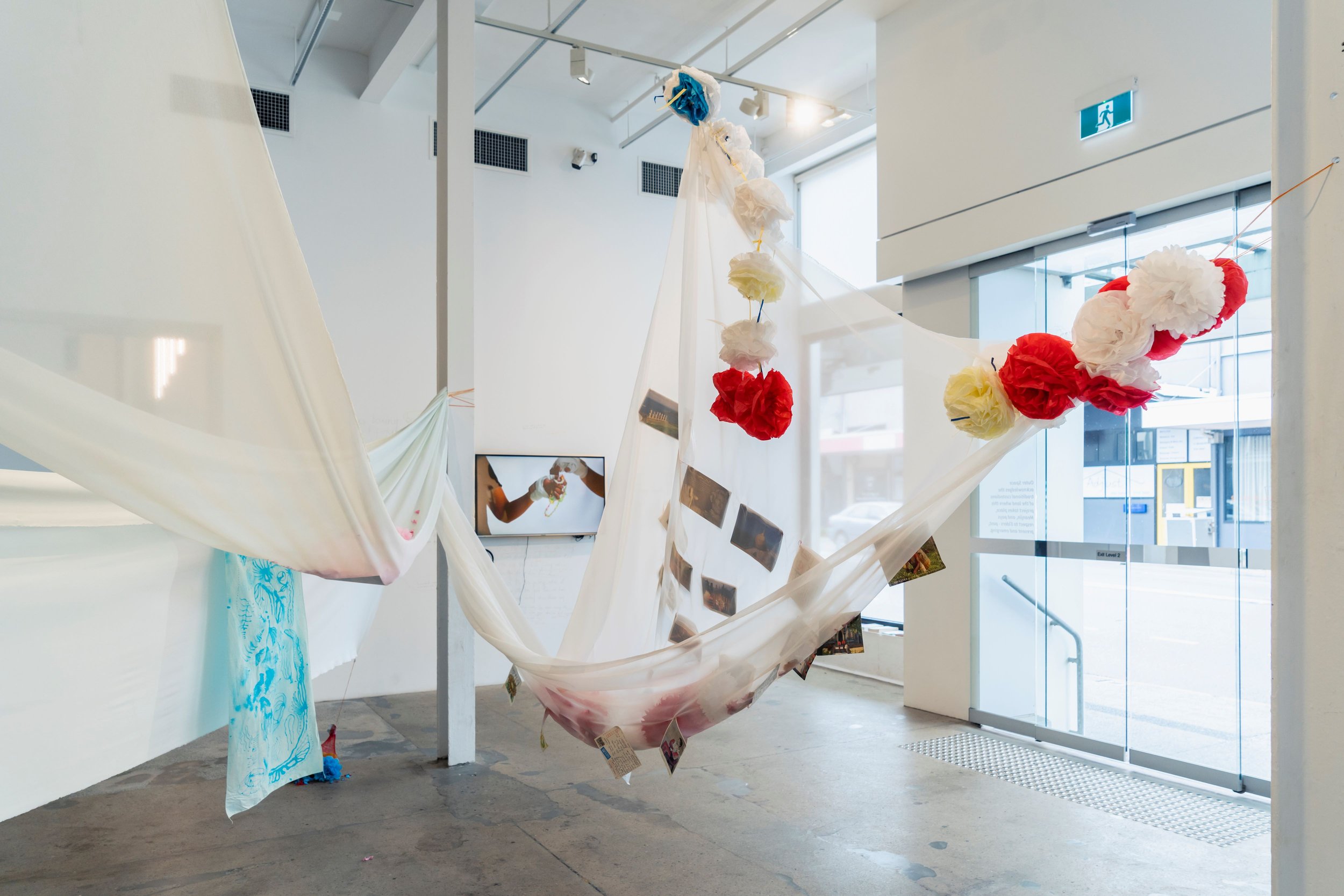   Postcards between the Takeuchis , 2021-2023. Installation, cotton, batik on silk, postcards, kirigami [paper flowers]. Dimensions variable. Photograph by Louis Lim. Courtesy the artist. 