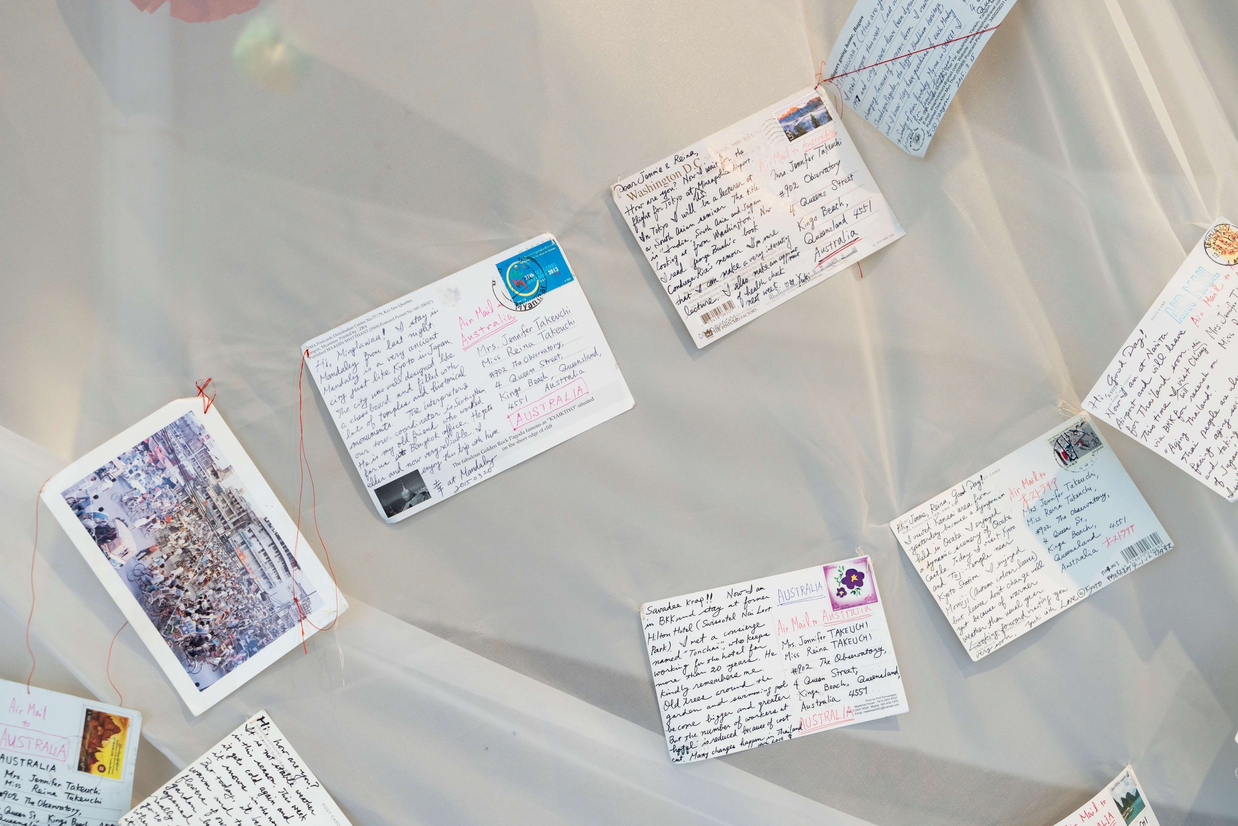   Postcards between the Takeuchis,  2021-2023. Installation, cotton, batik on silk, postcards, kirigami [paper flowers]. Dimensions variable. Photograph by Louis Lim. Courtesy the artist. 