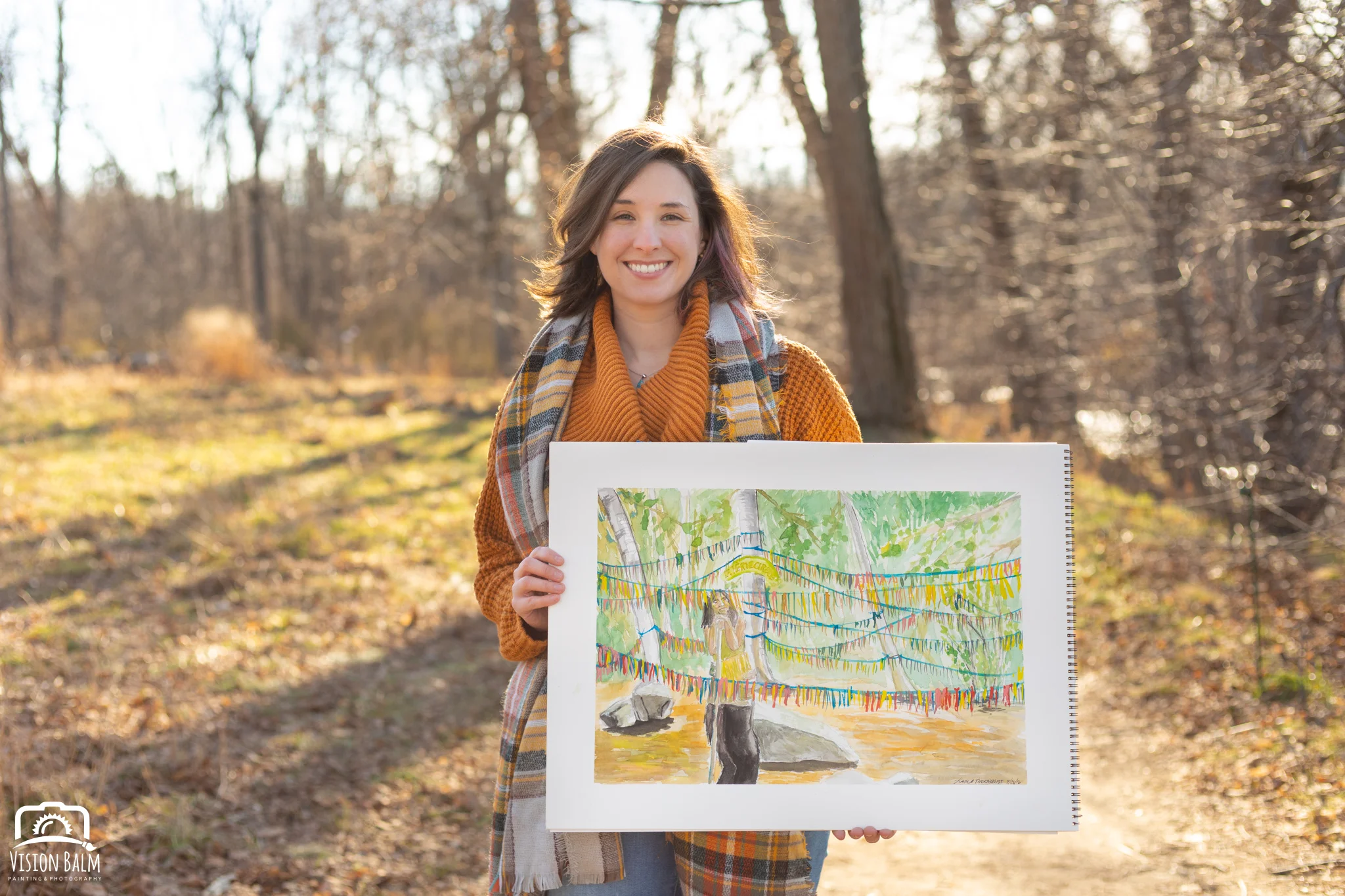 Professional fall portrait photography of Kayla Thornquist comic book artist and illustrator wearing an orange sweater in the park and holding her artwork photographed by Vision Balm in Charleston, SC.