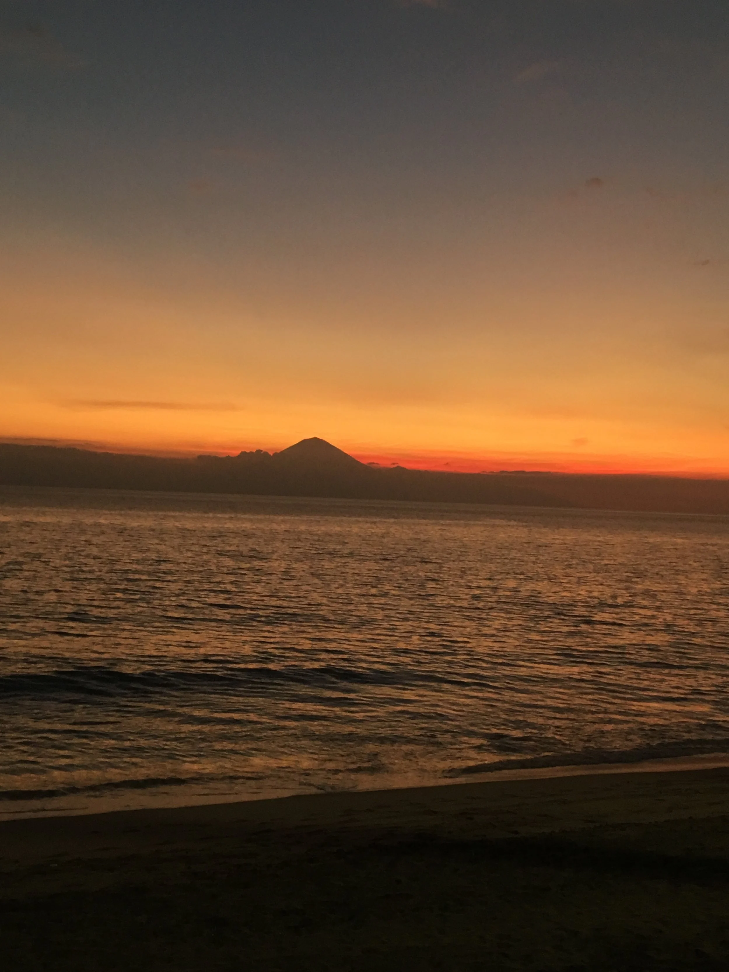  Sunset on the beach, with a view of  Gunung Agung in Bali across the Bali Sea.  