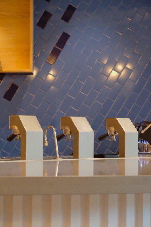 Houndstooth Coffee NorthSide counter with three sleek espresso machines against a blue tiled wall.