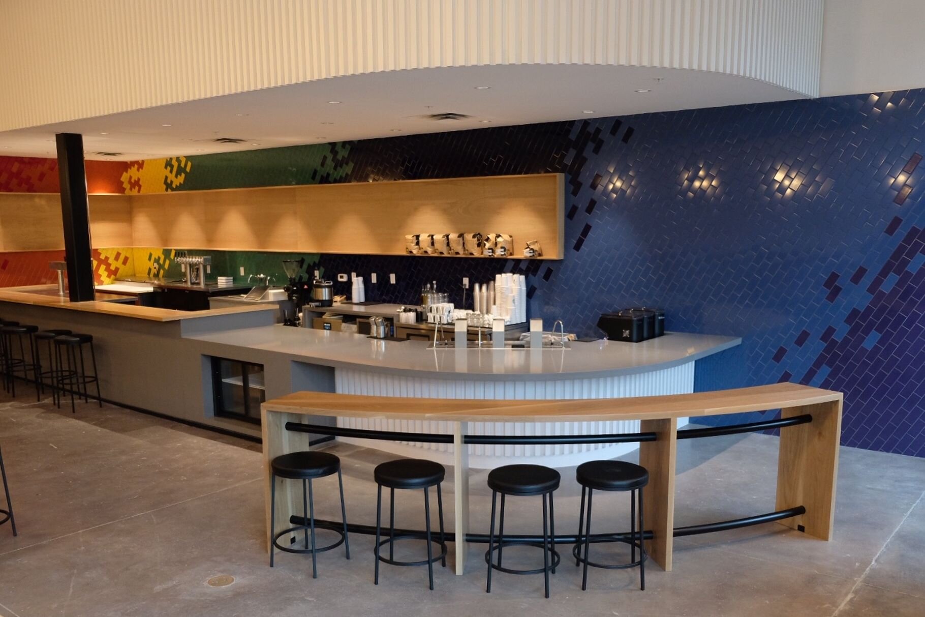 Houndstooth Coffee NorthSide interior featuring a sleek rounded counter, stools, and colorful tile walls.