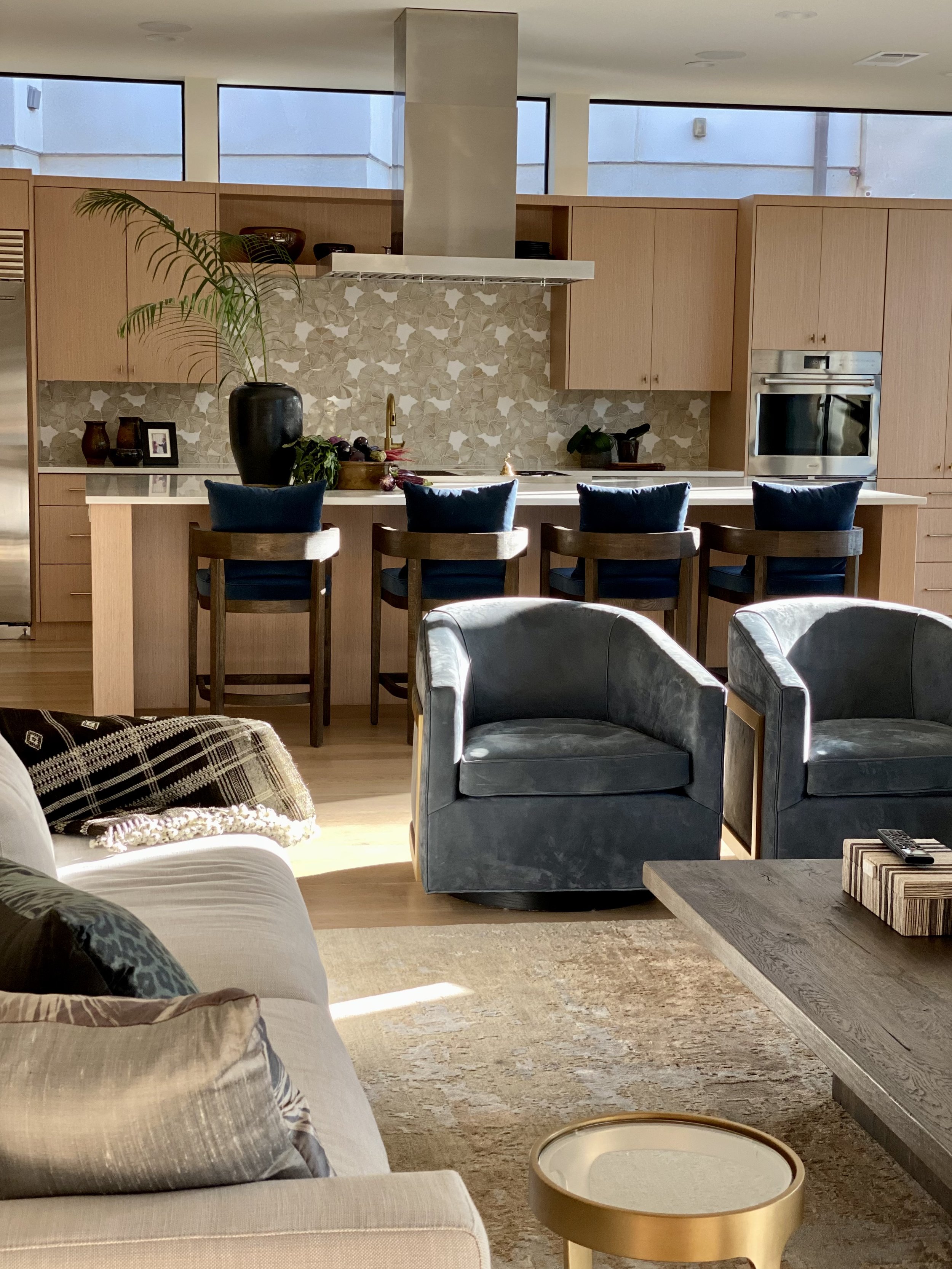 Kitchen and living area in a Barton Creek home with bar stools, blue armchairs, patterned pillows and lots of natural light.