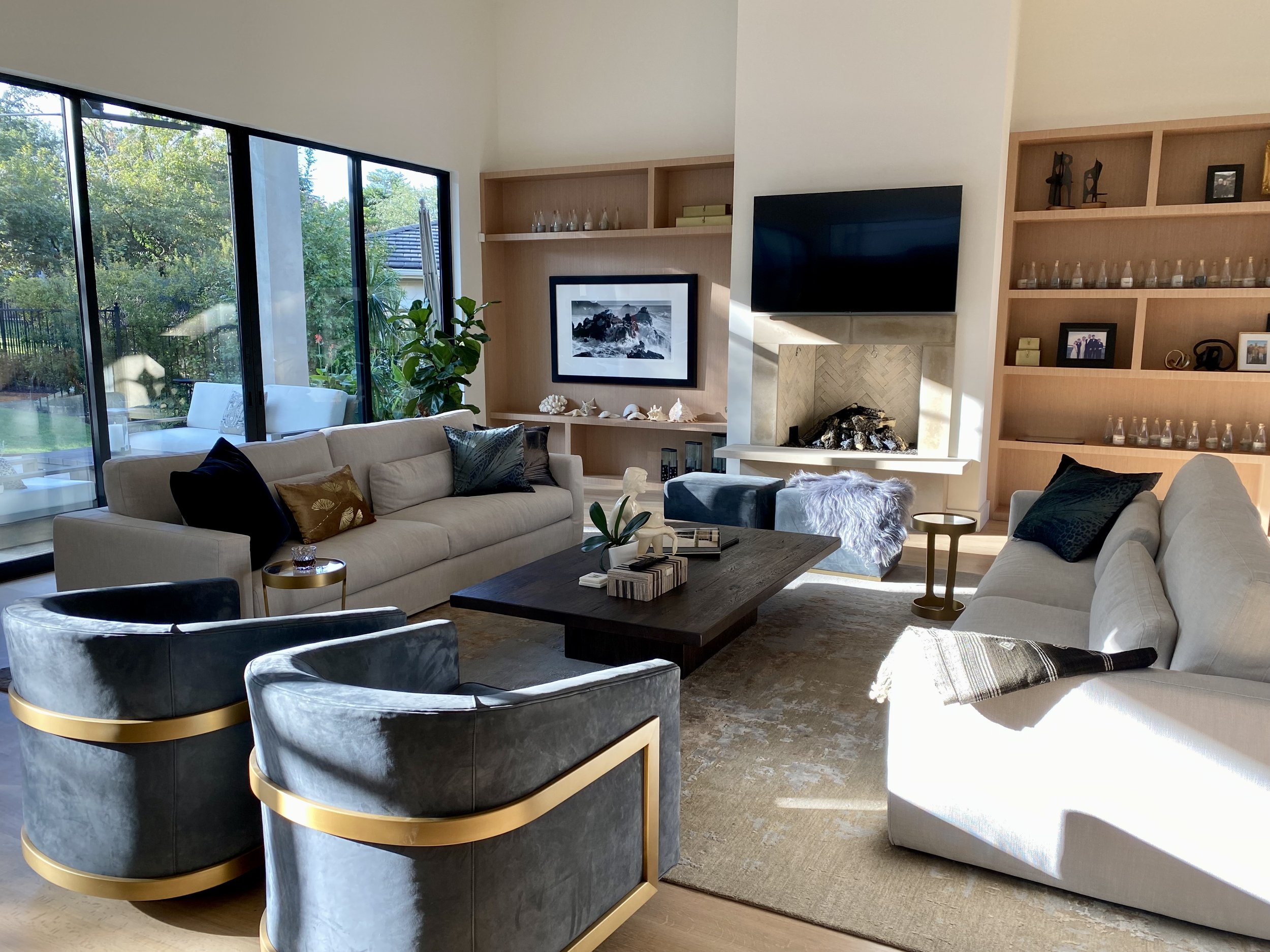 A living room in a Barton Creek home with two couches, two armchairs, a coffee table, built-in shelves, and large windows providing natural light.