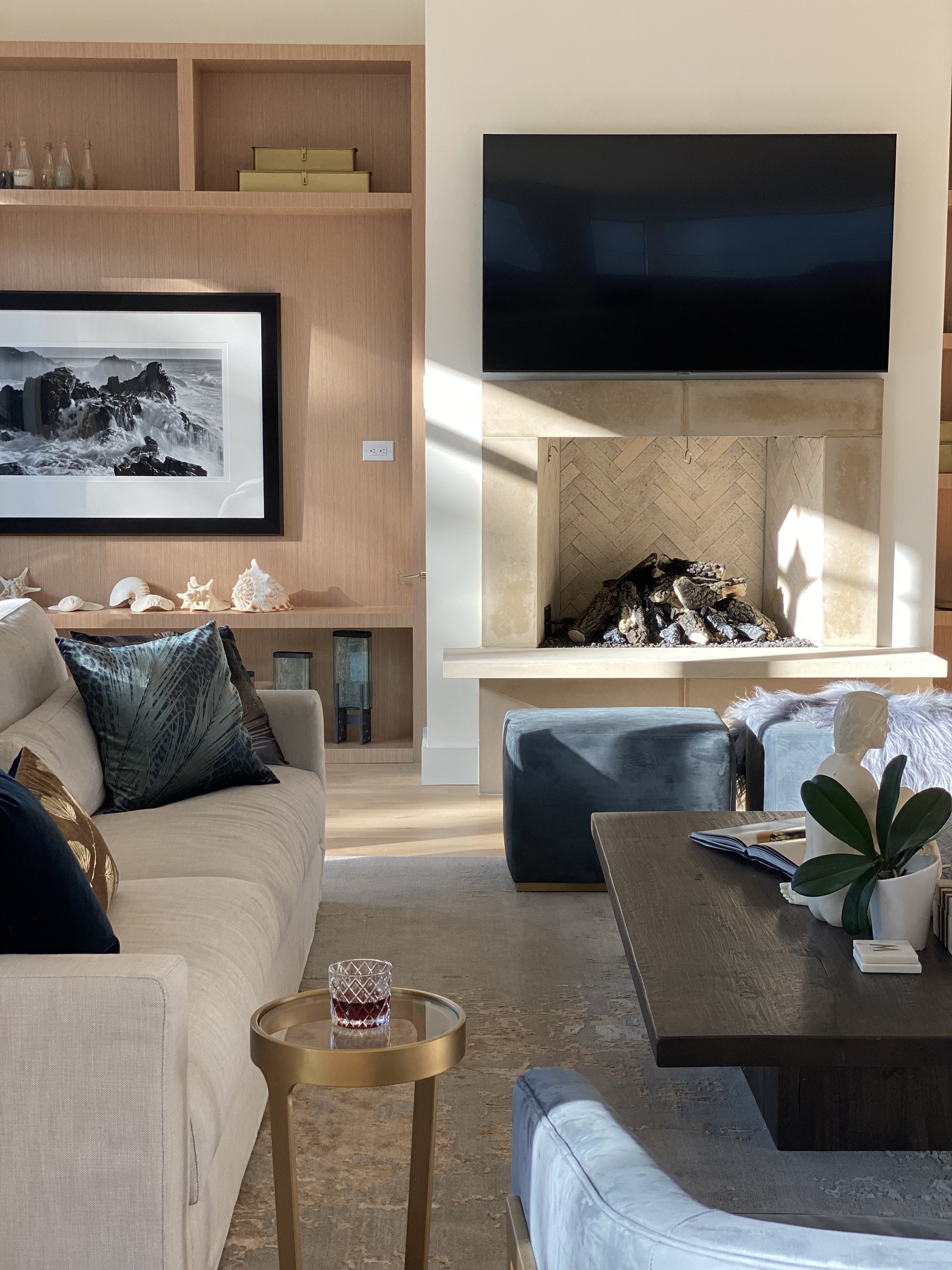 Living room in a Barton Creek home with light gray sofa, wall-mounted TV above the fireplace, and wooden shelves.
