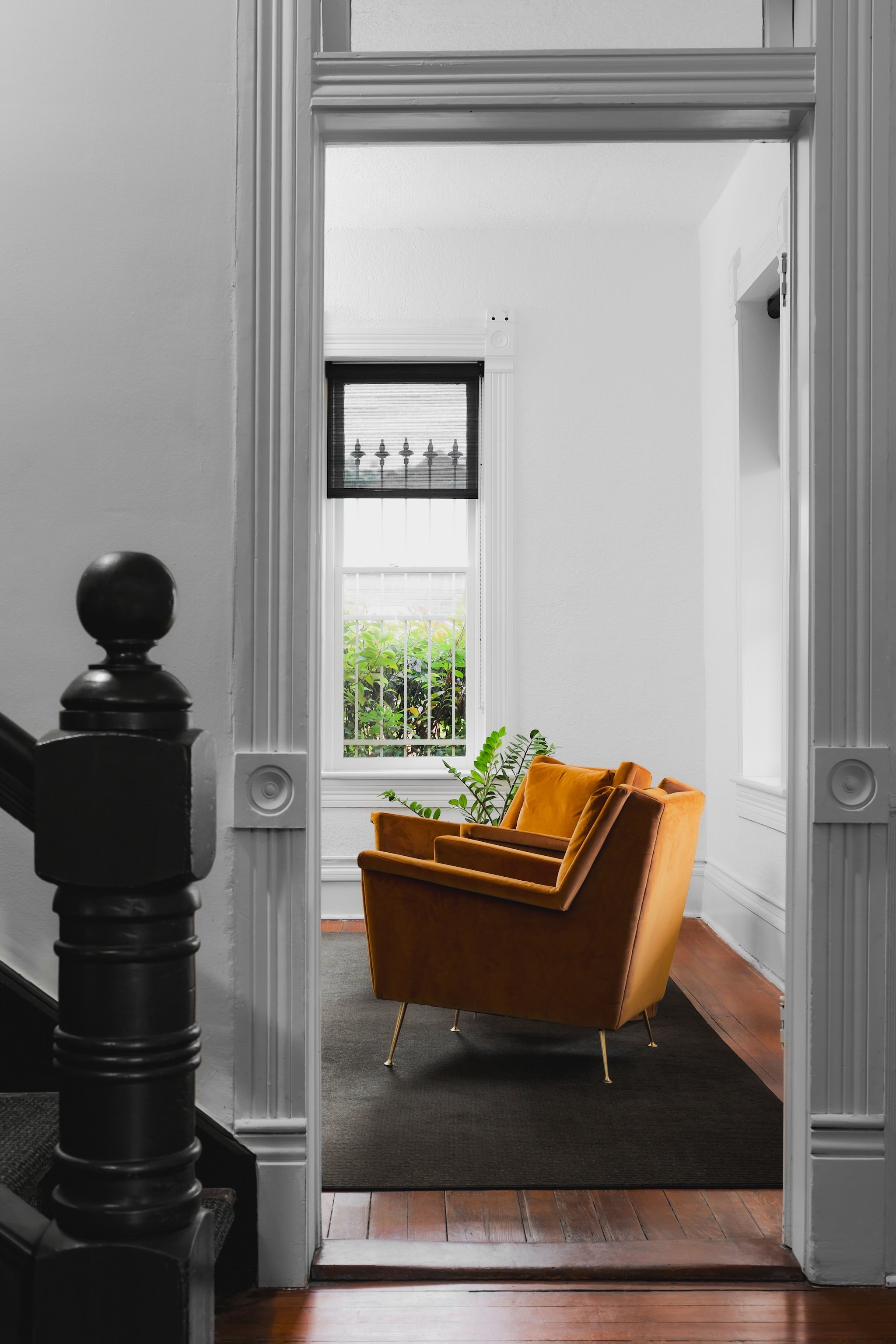 Two colorful armchairs in front of a window in a bright, minimalistic room in a law firm viewed through a doorway.