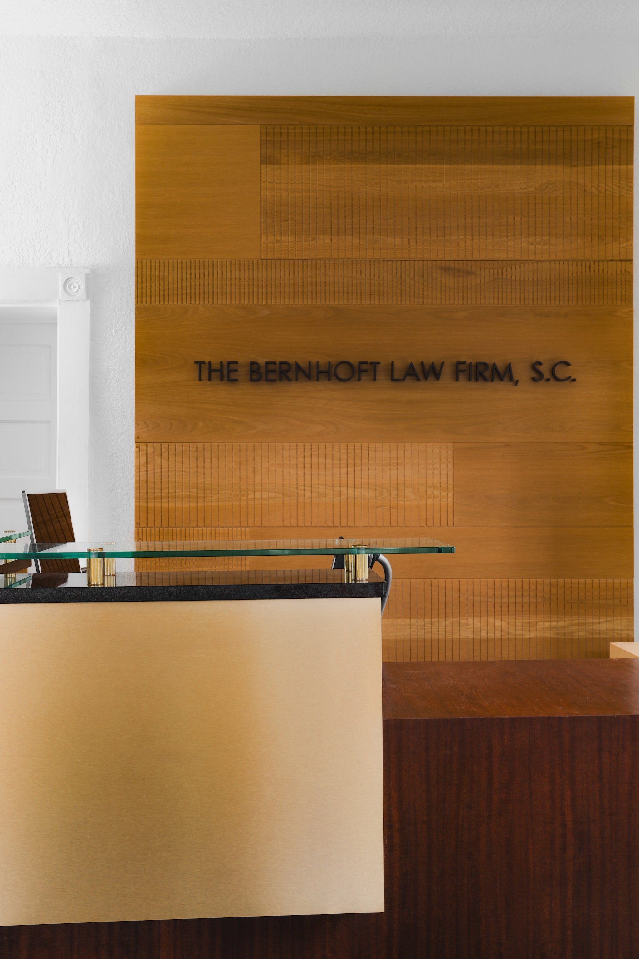 Reception desk in a law firm in front of sign lettering mounted on a wooden wall.