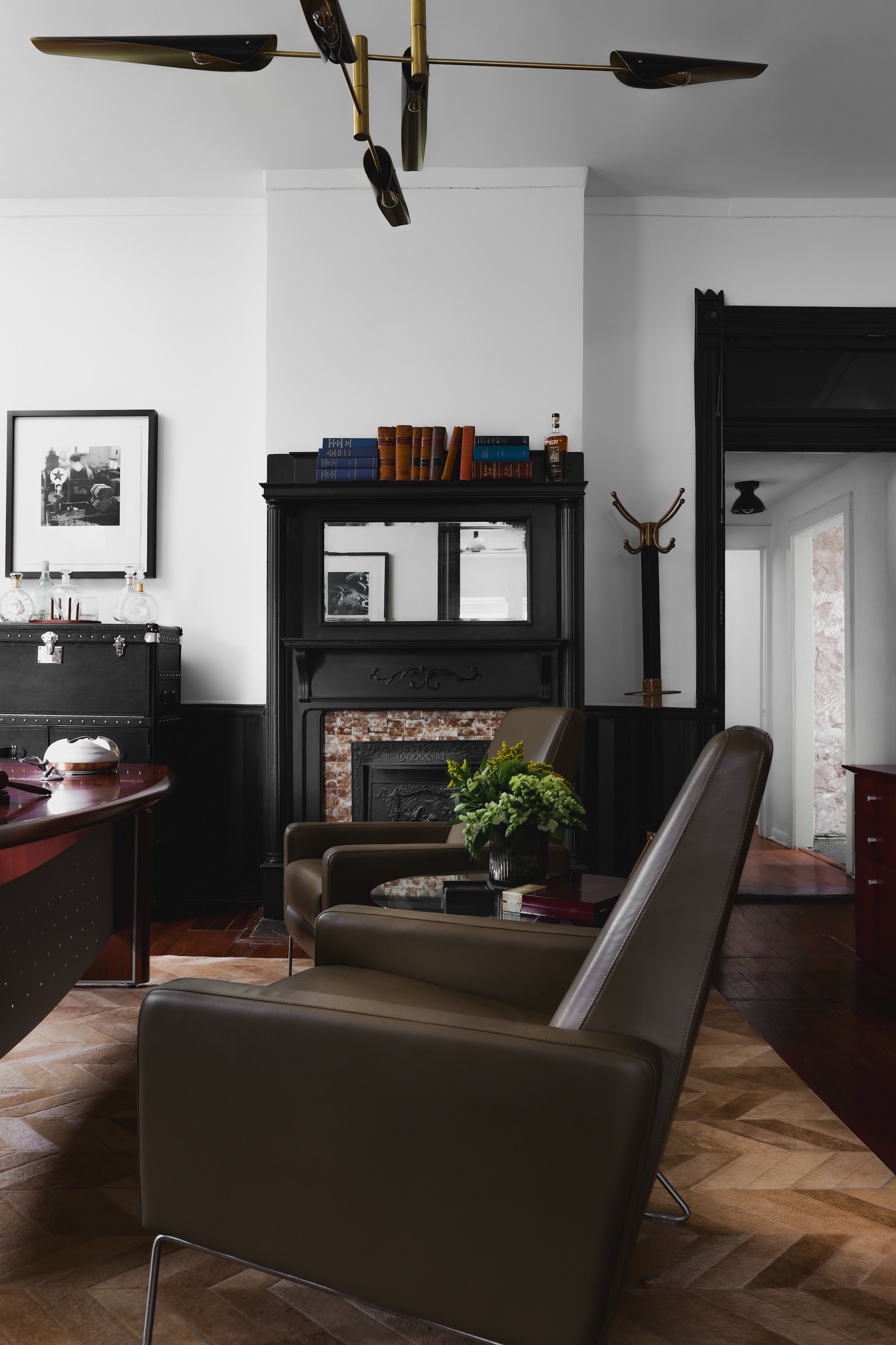An office space in a law firm with a black fireplace, brown leather chairs, framed photos, and books on the mantel.