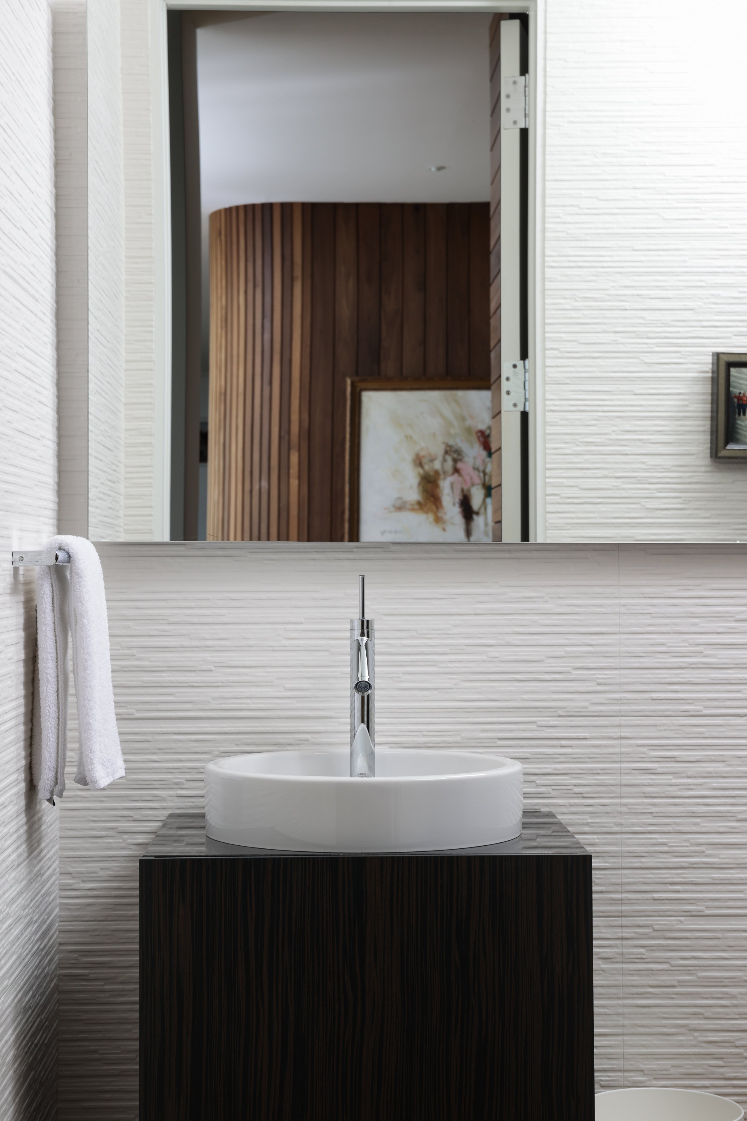 Bathroom in a Laurel Canyon home with a round sink on a dark wood vanity, large mirror, and white textured walls.
