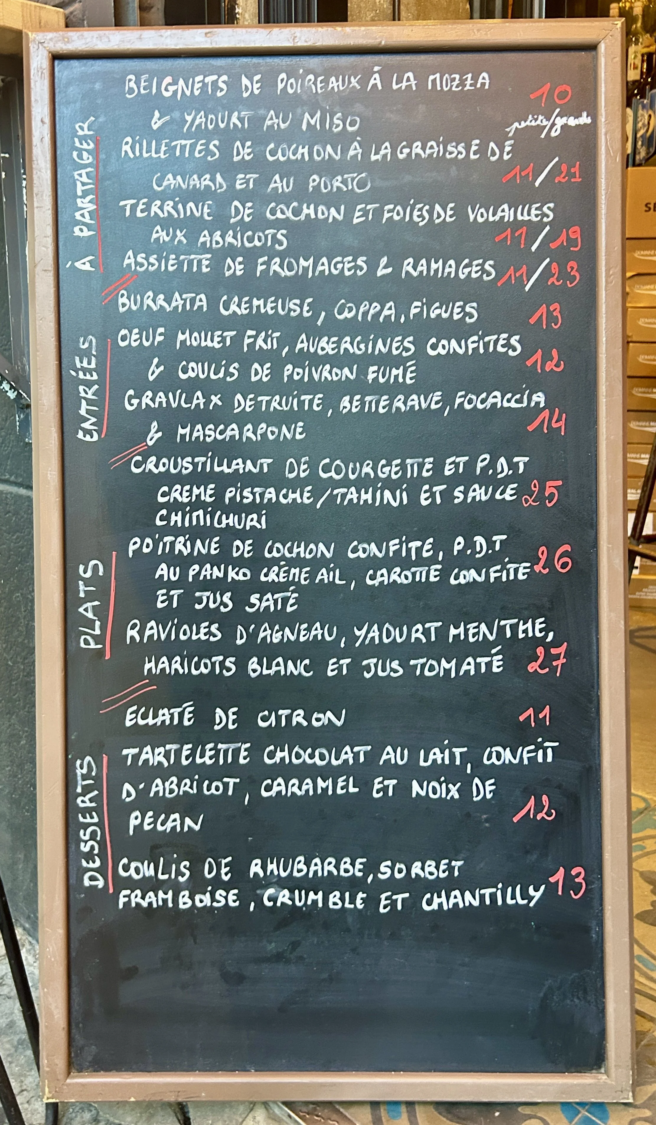 Menu de plats et desserts écrit à la craie sur un tableau noir dans un restaurant ou café, listant différentes options culinaires avec leurs prix.