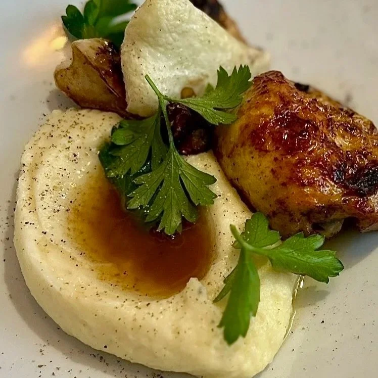 Purée de pommes de terre garnie de persil frais, un morceau de poulet rôti et un peu de sauce.