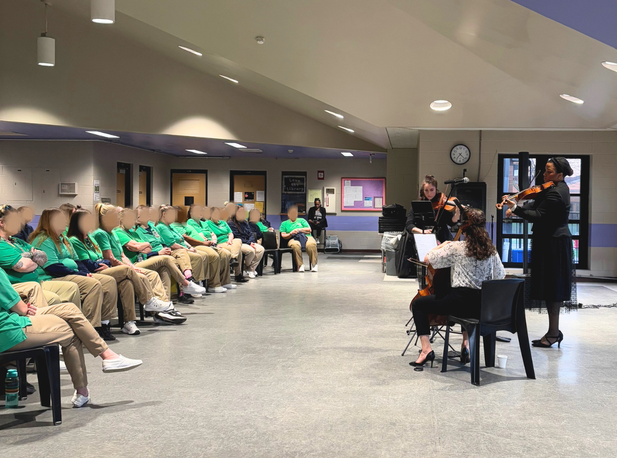 The Renovare trio perform on violin, viola, and cello for a room full of people at the women's prison in Cleveland.