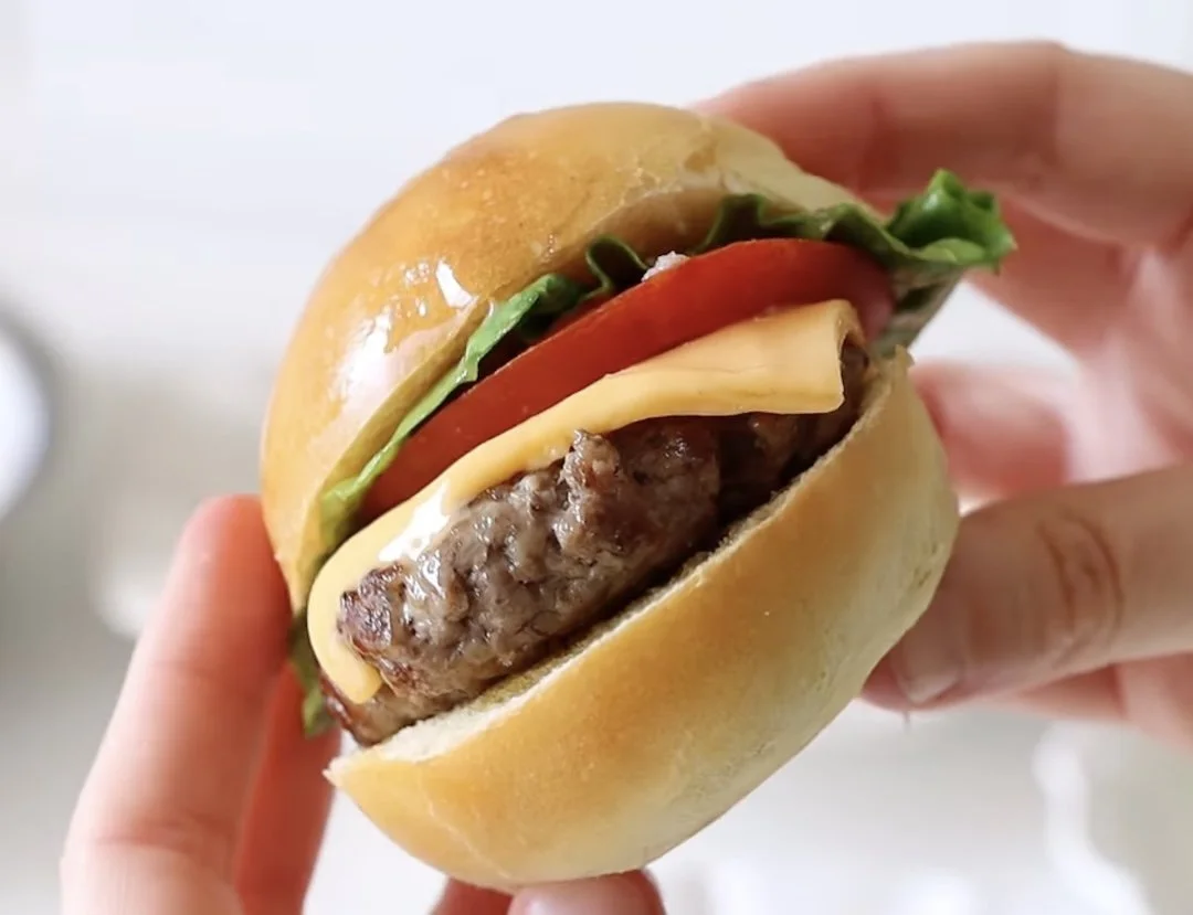 A slider, with beefy patty, cheese, lettuce and tomato.