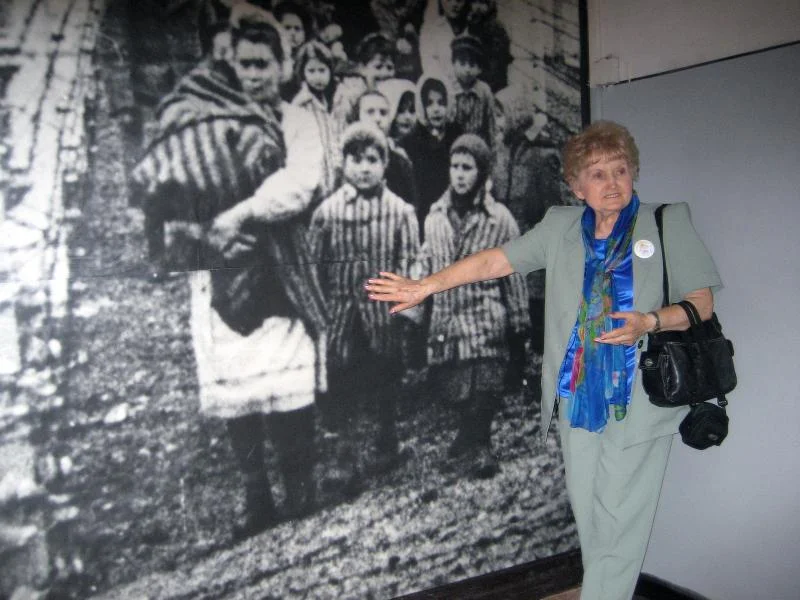 Eva Kor in front of a picture of herself as a child in Auschwitz