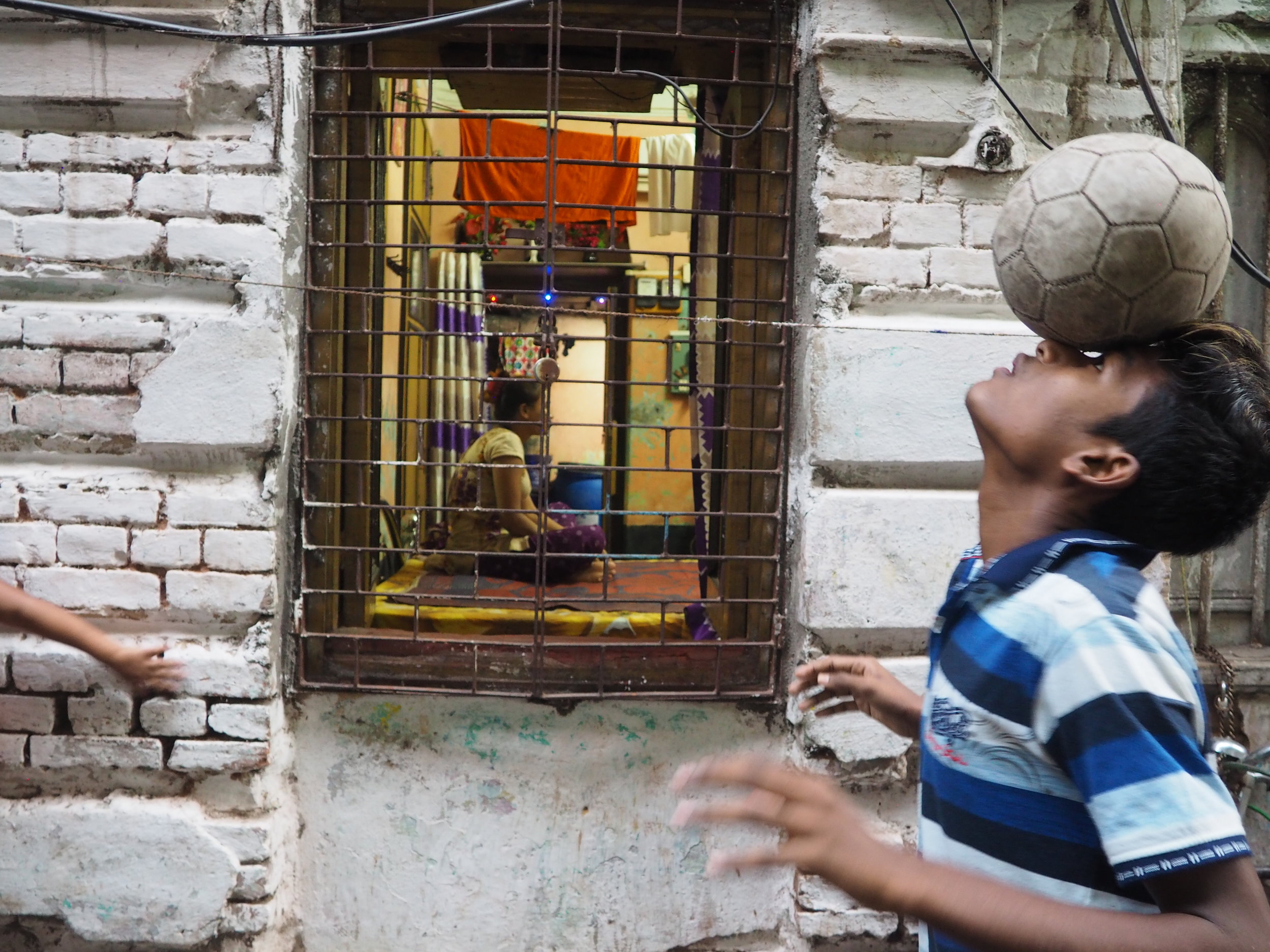  A Durbar footballer practices in an alleyway of Sonagachi while a sex worker looks on. 