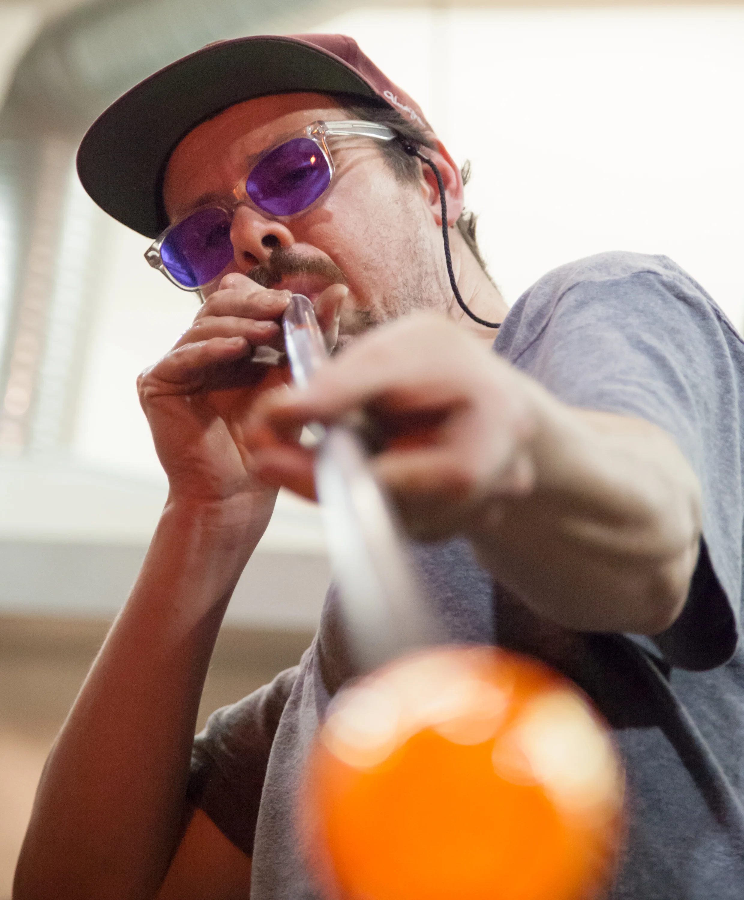 To make each glass, I first gather liquid glass from a large furnace onto the end of a stainless steel pipe. I then blow air through the pipe and into the white-hot glass, forming a bubble.