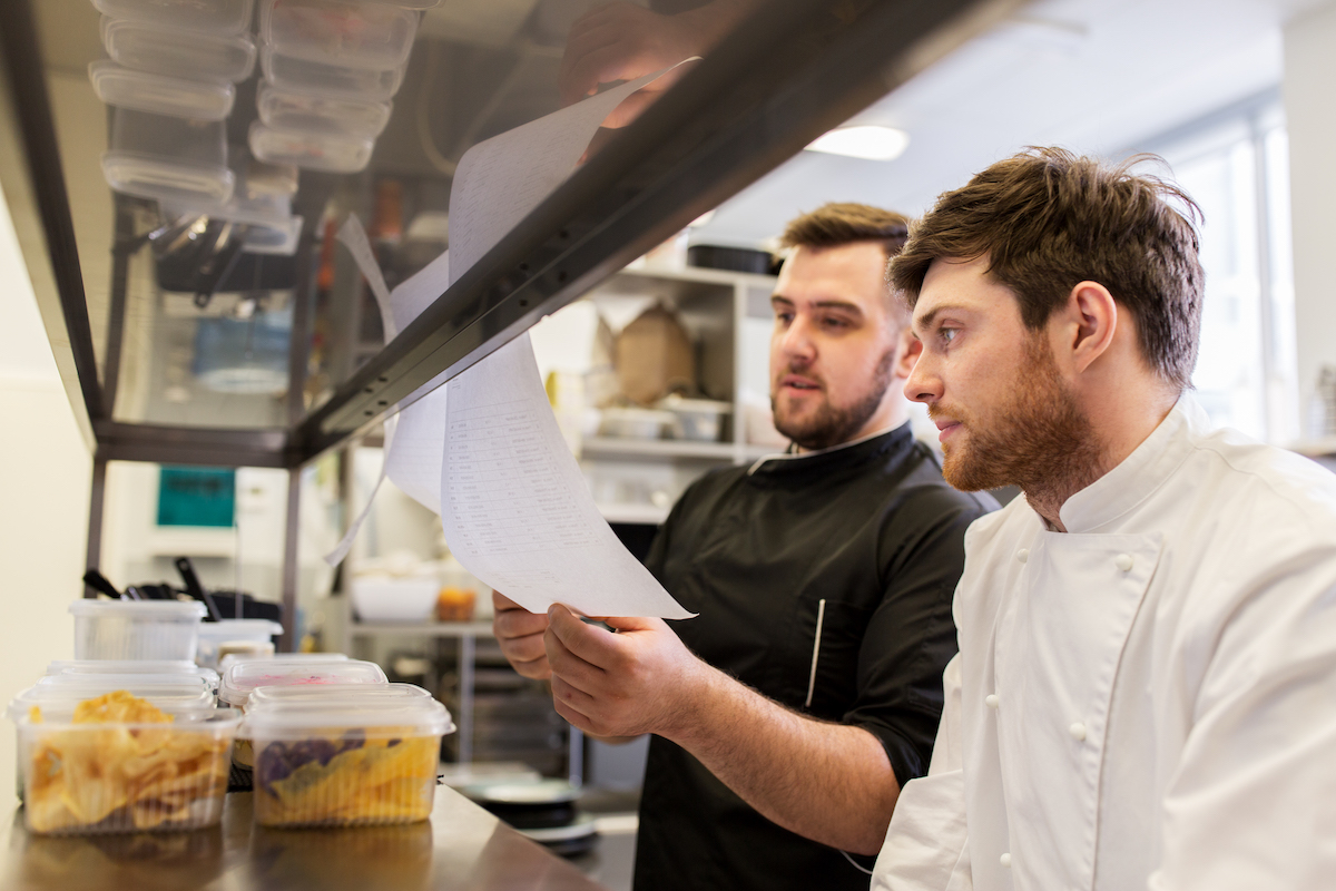 chef-and-cook-with-lists-or-bills-at-kitchen-PF8HNHQ.jpg