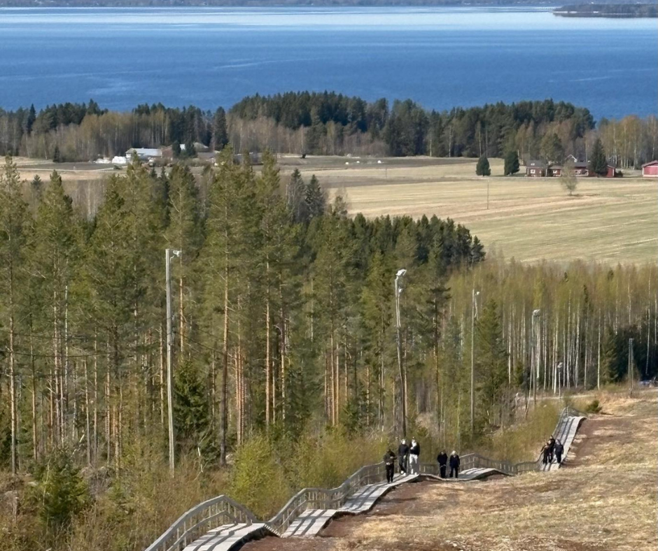 maisema jossa taustalla järvi ja lukiolaisia nousee ylös kuntoportaita rinnettä pitkin