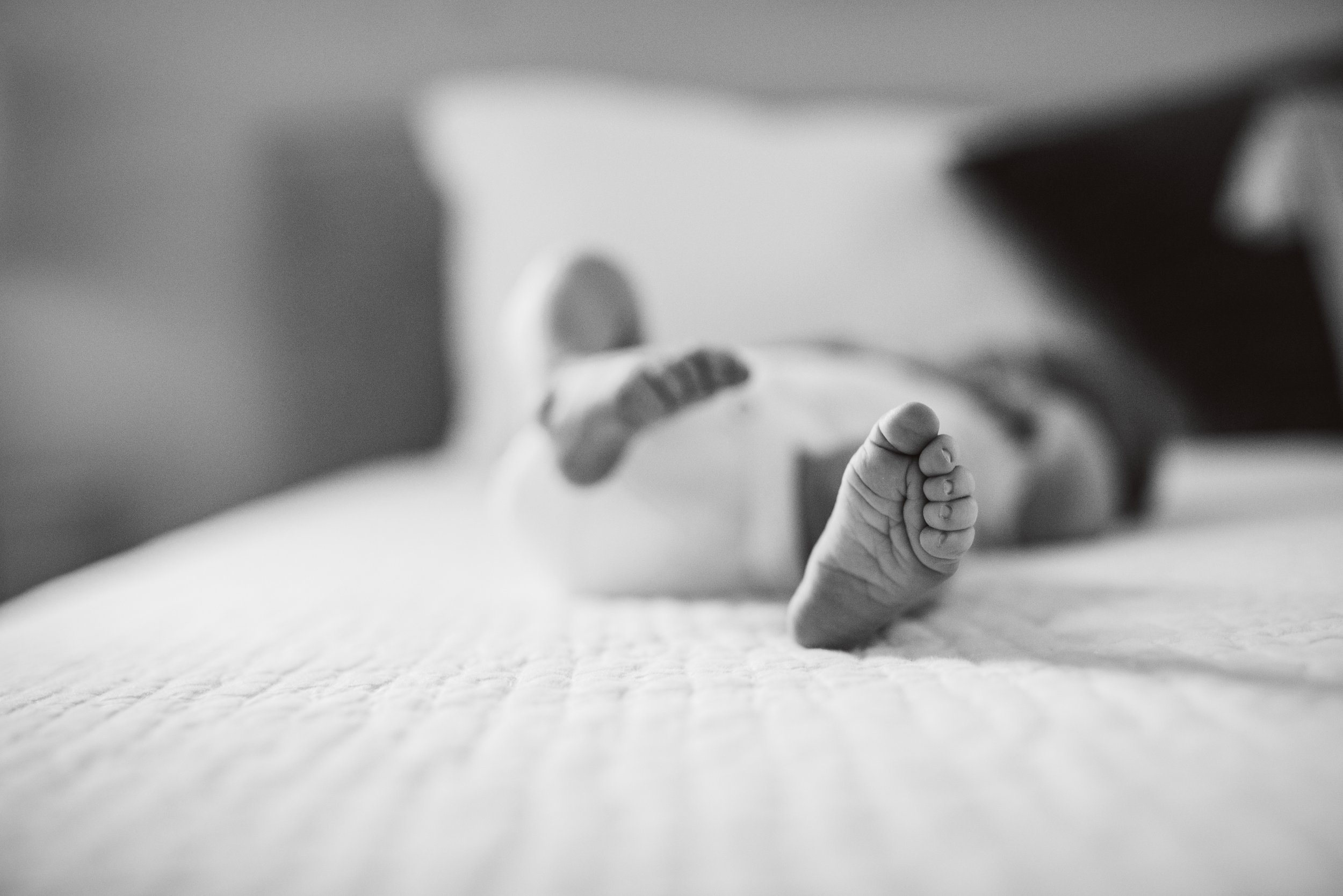 Baby foot on master bed, black and white