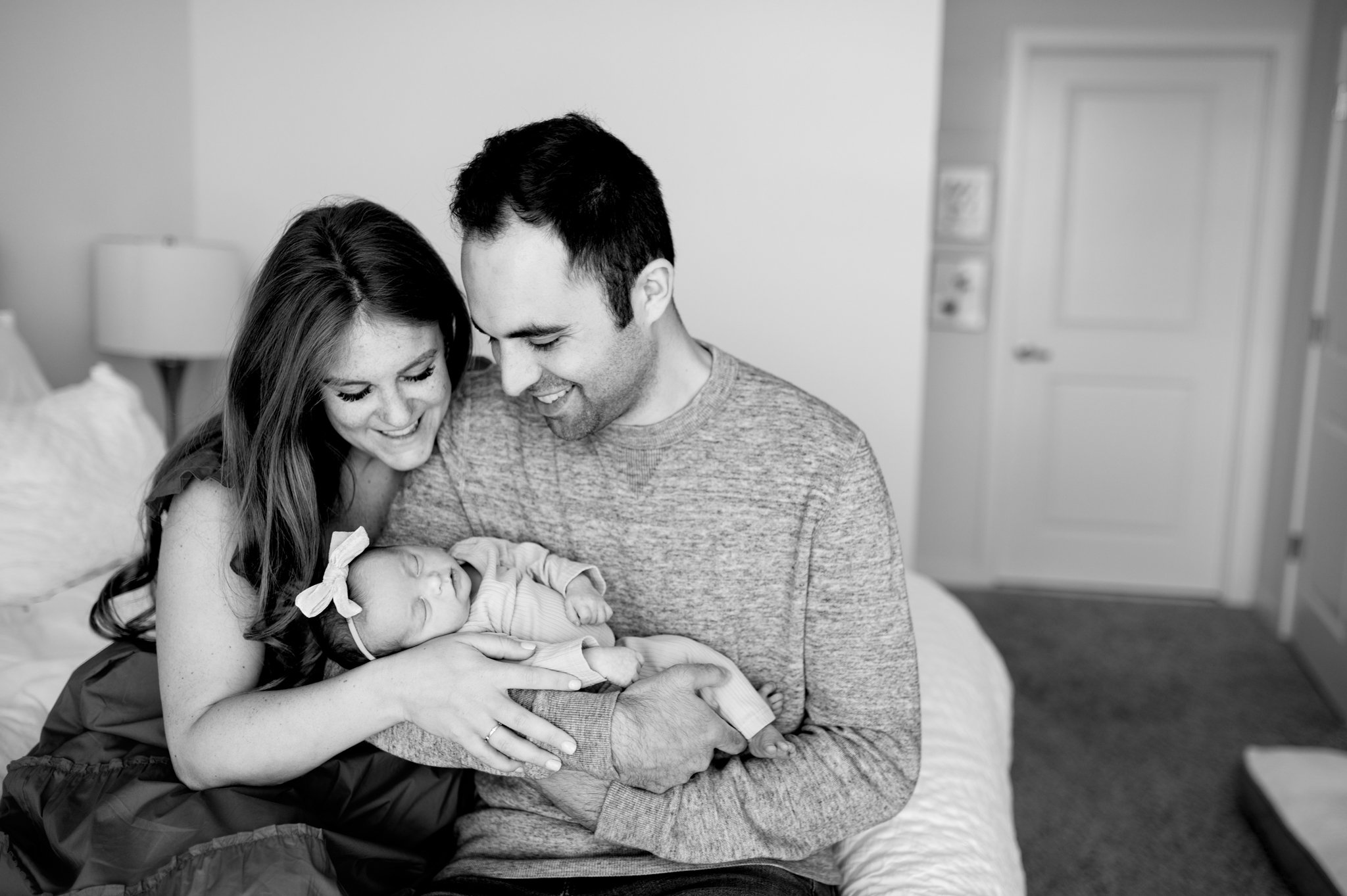 Parents snuggle their baby girl, black and white