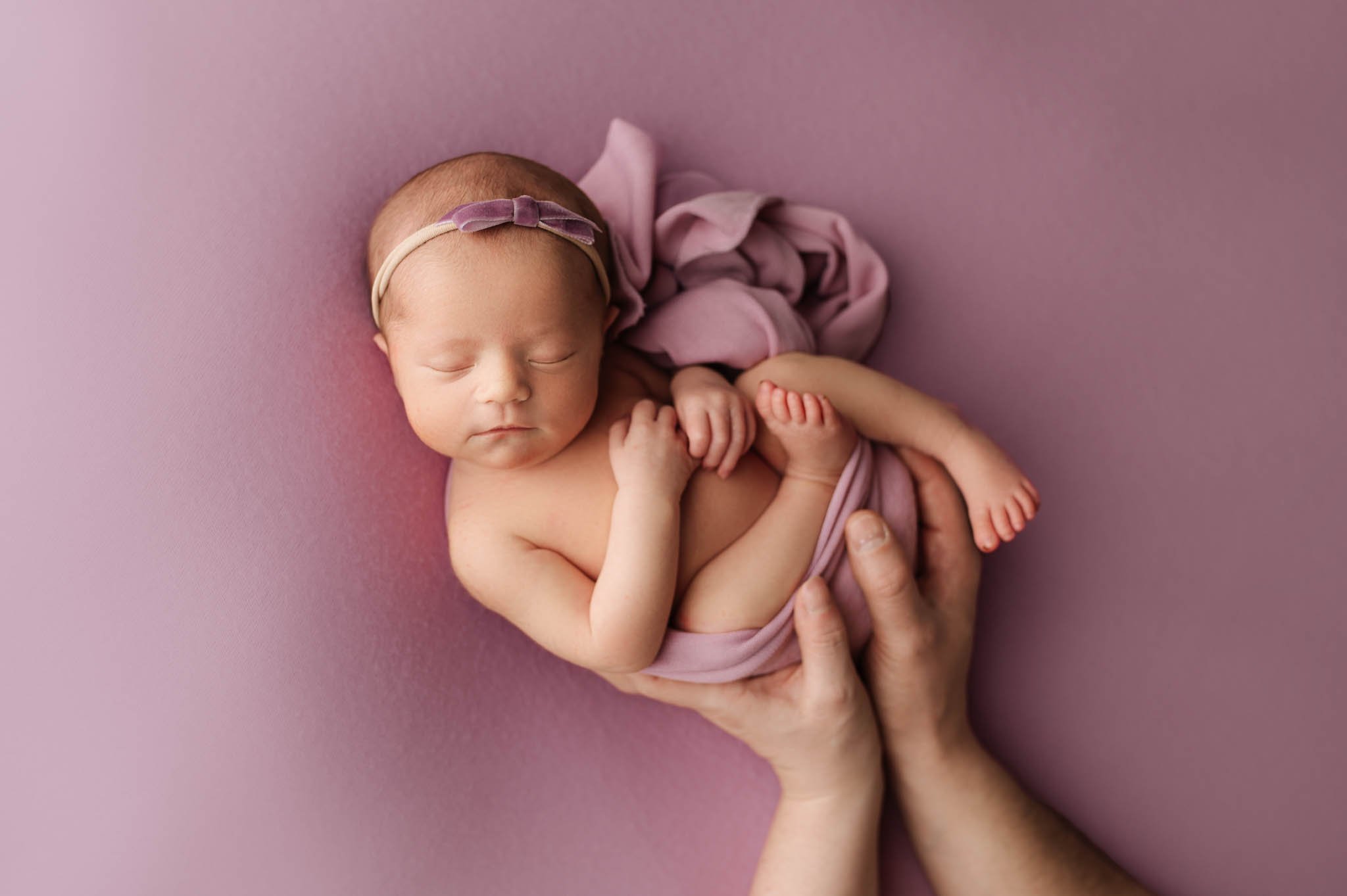 Baby girl girl on purple blanket with wrap and parent hands