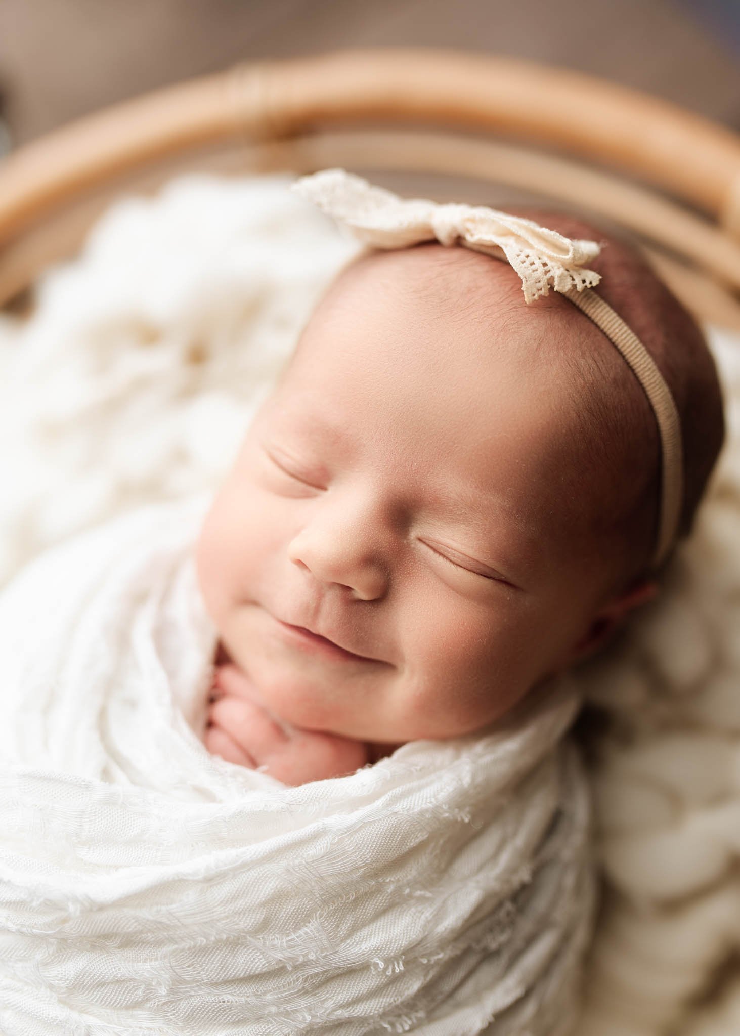 Smiling baby in white wrap and bow headband