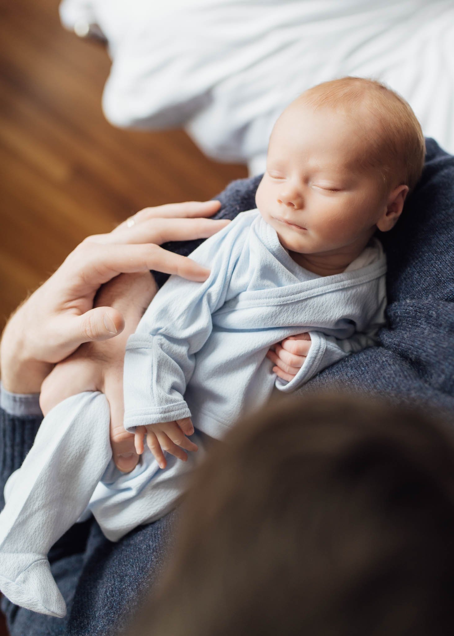 Baby boy in blue outfit being held by dad