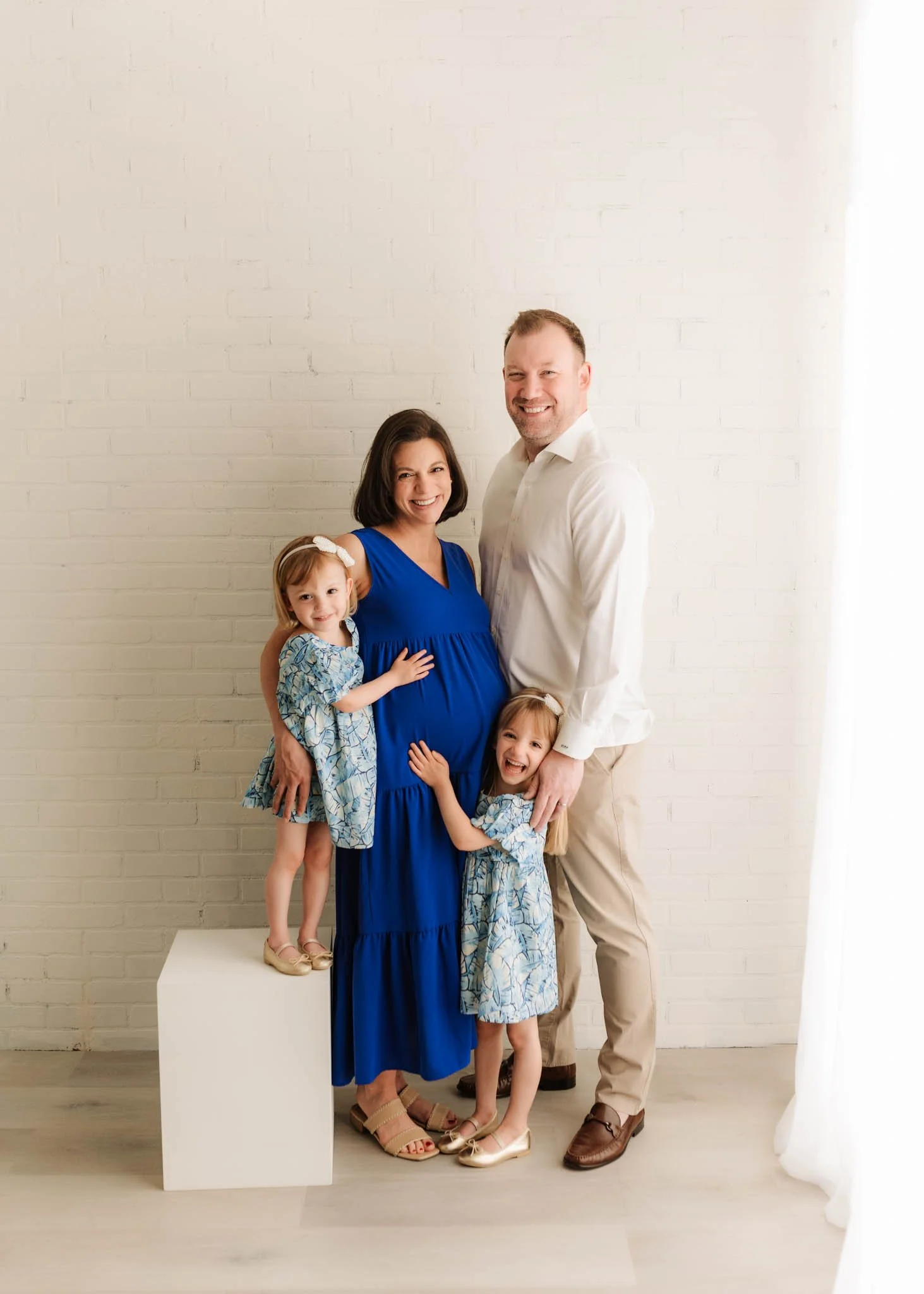 two parents and two little girls pose in ridgefield studio for maternity photoshoot