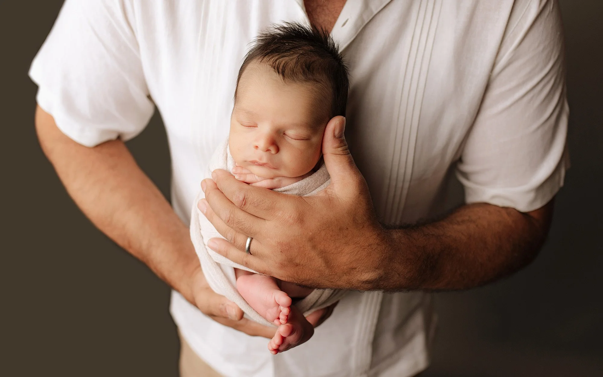 newborn baby is held by dad's arms in Fairfield County, ct photography studio