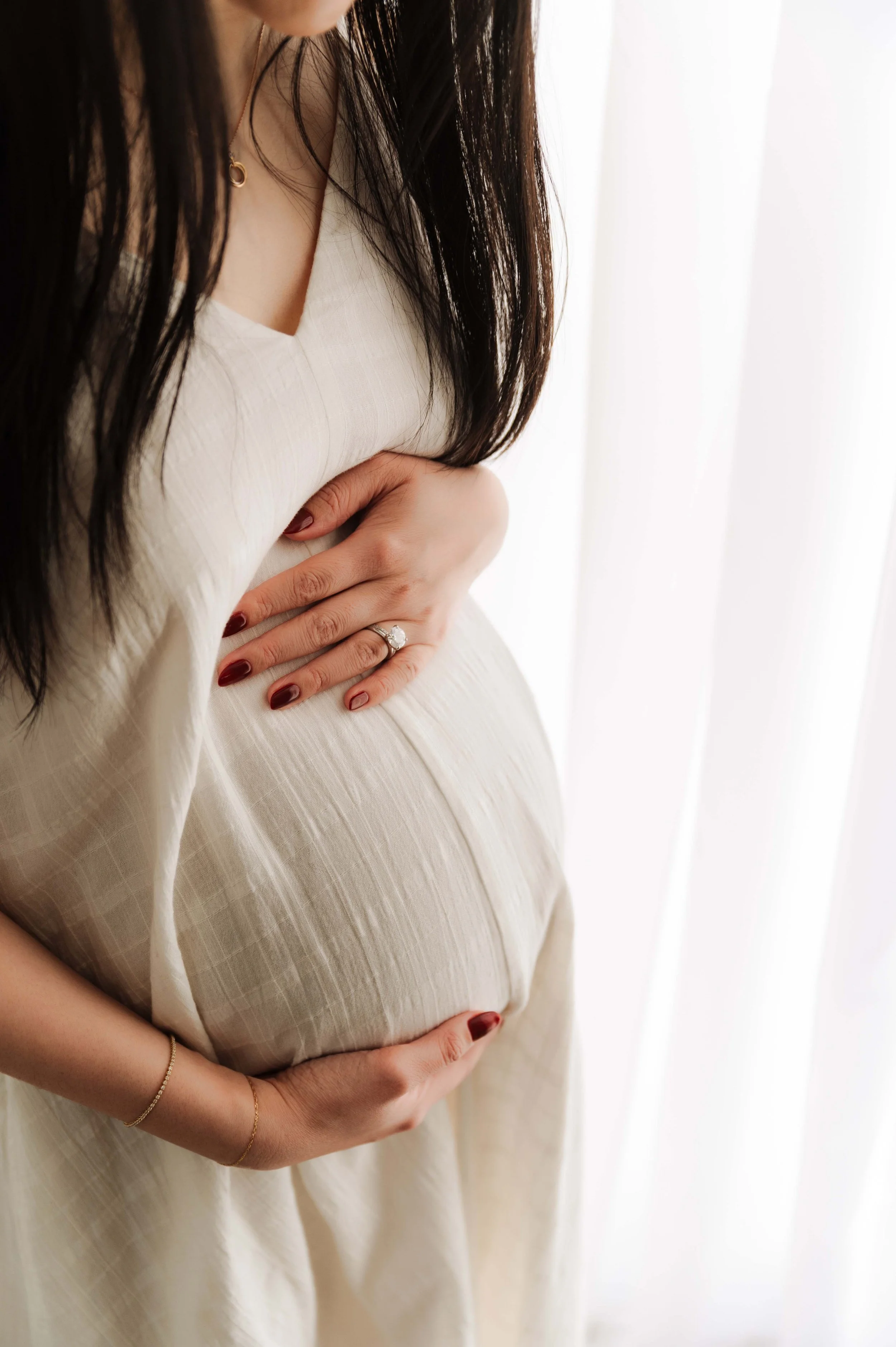 closeup of pregnant woman's belly, framed by her hair and hands, in ridgefield, ct studio