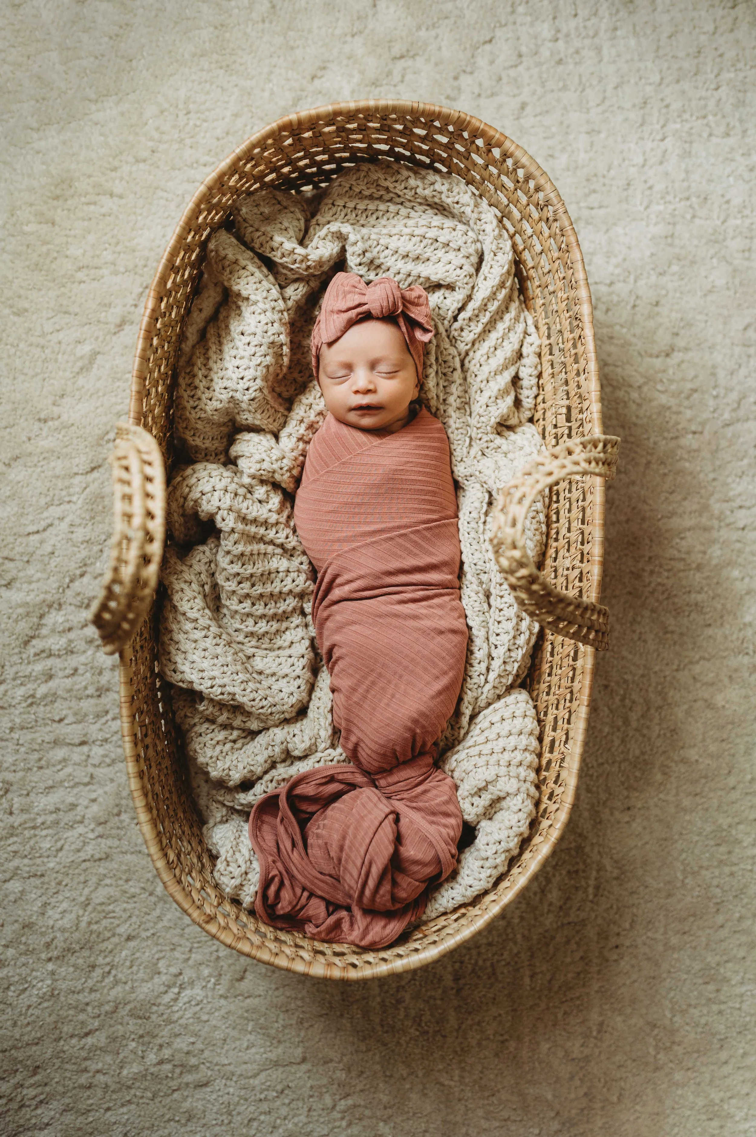 baby girl in pink blanket sleeps in wicker basket in an in-home lifestyle newborn session