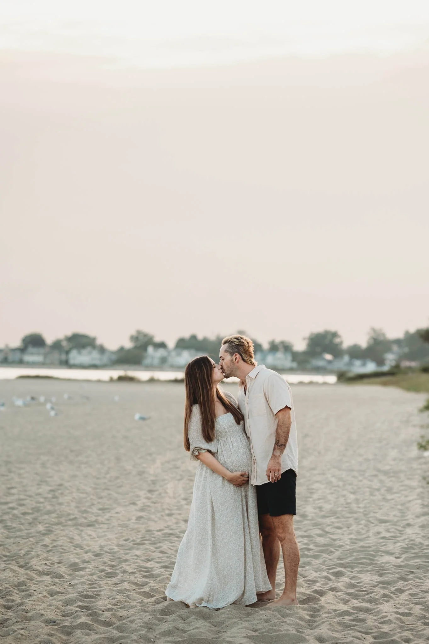 expecting couple kisses on fairfield county beach, maternity photoshoot