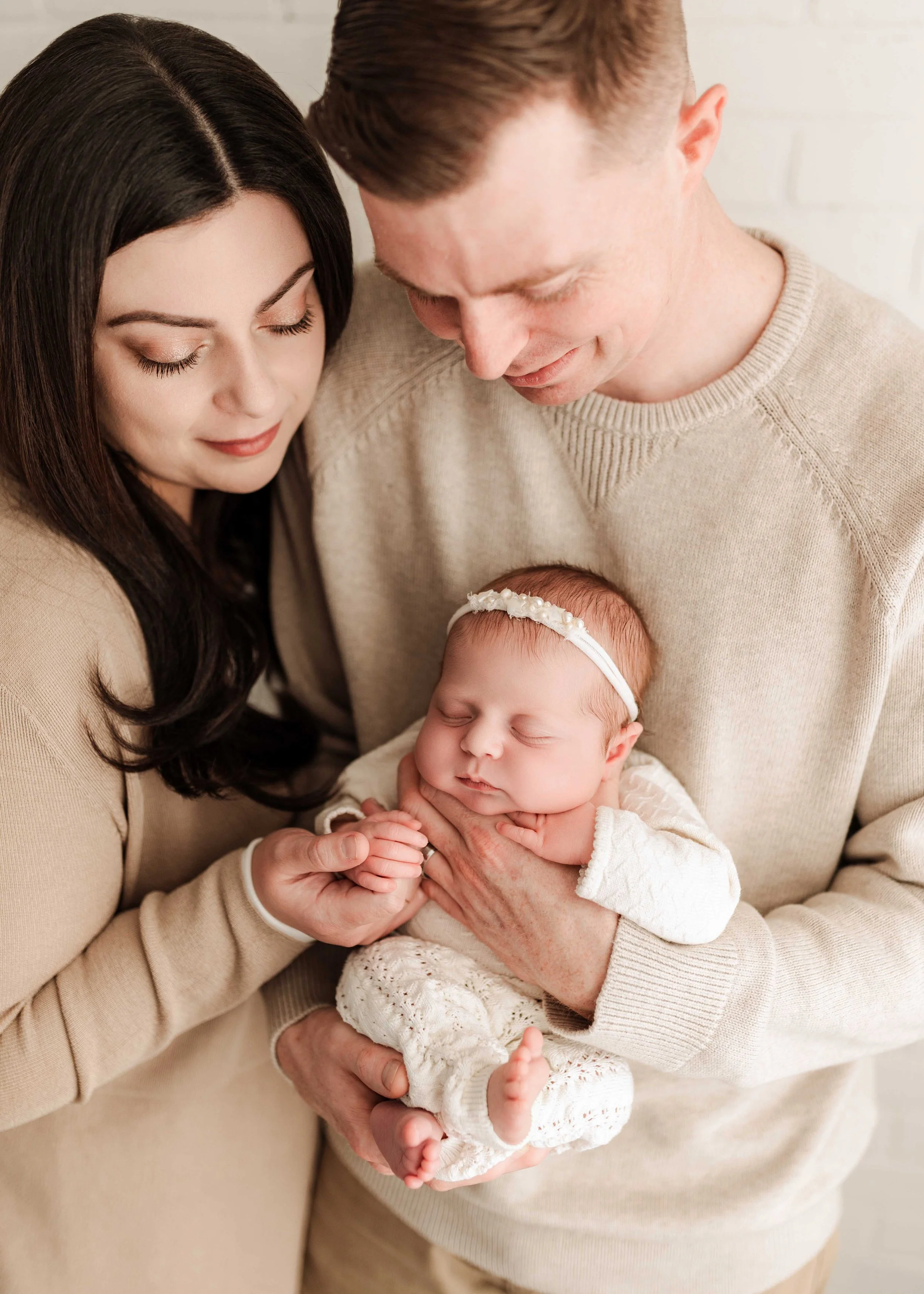 parents hold baby girl dressed in white in ridgefield, ct studio