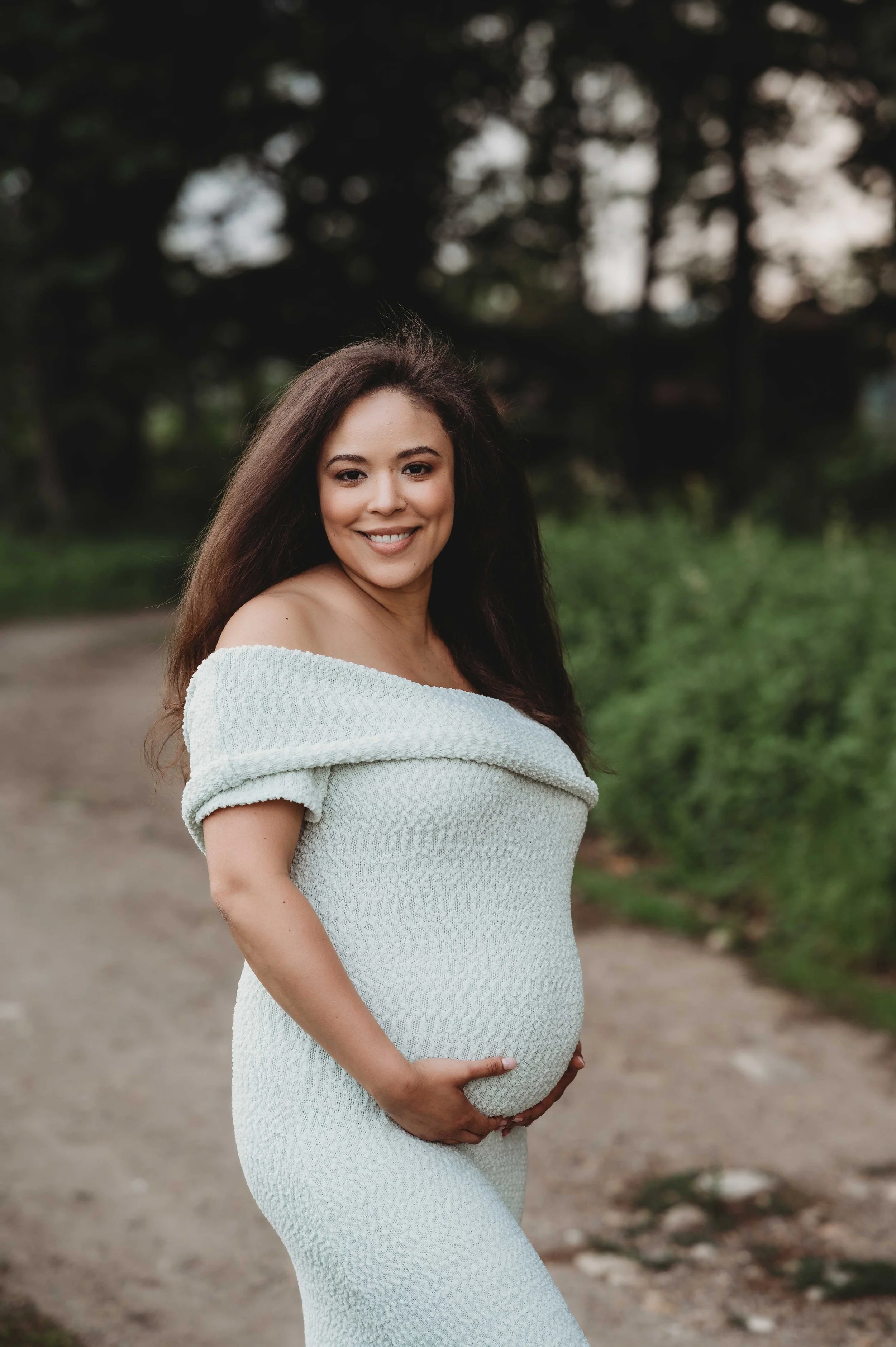 pregnant woman wearing fitted green dress poses on westport, ct beach for maternity photoshoot