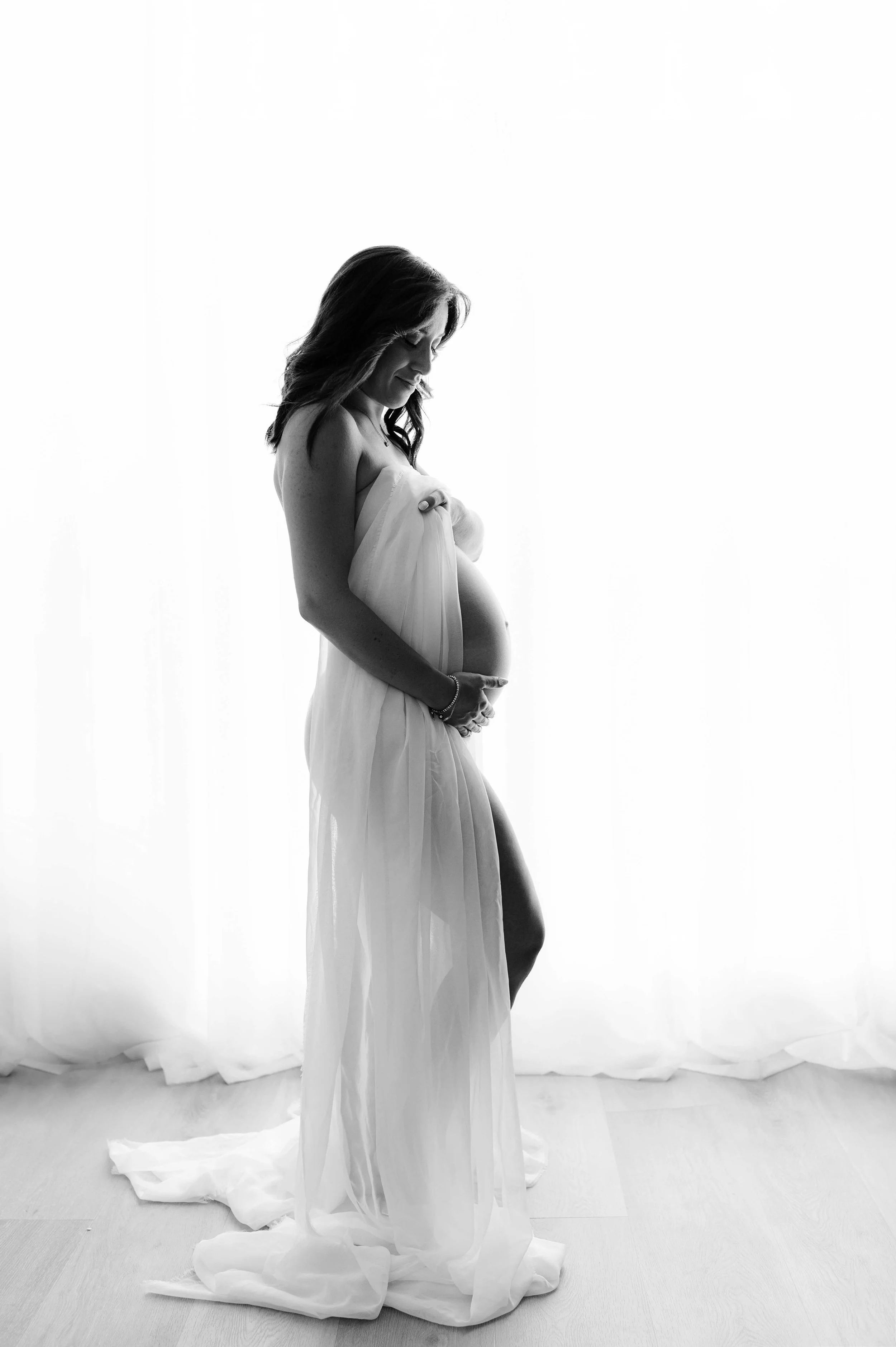 backlit image of pregnant woman cradling bump