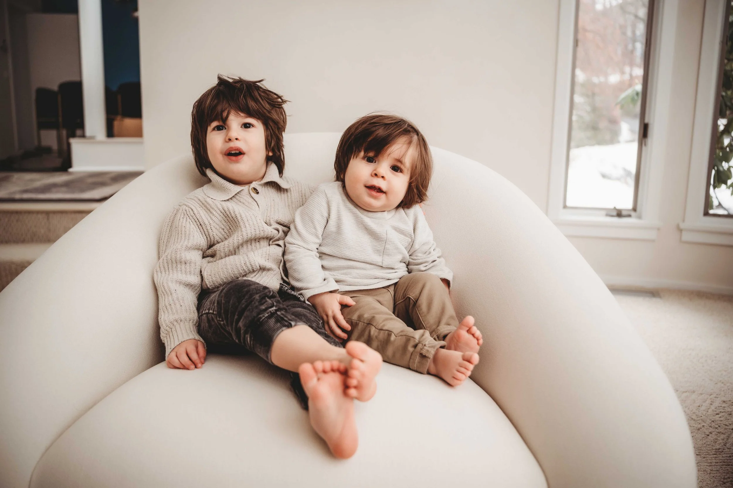 young boys wearing neutral colors sit in living room chair, chappaqua ny lifestyle photography session