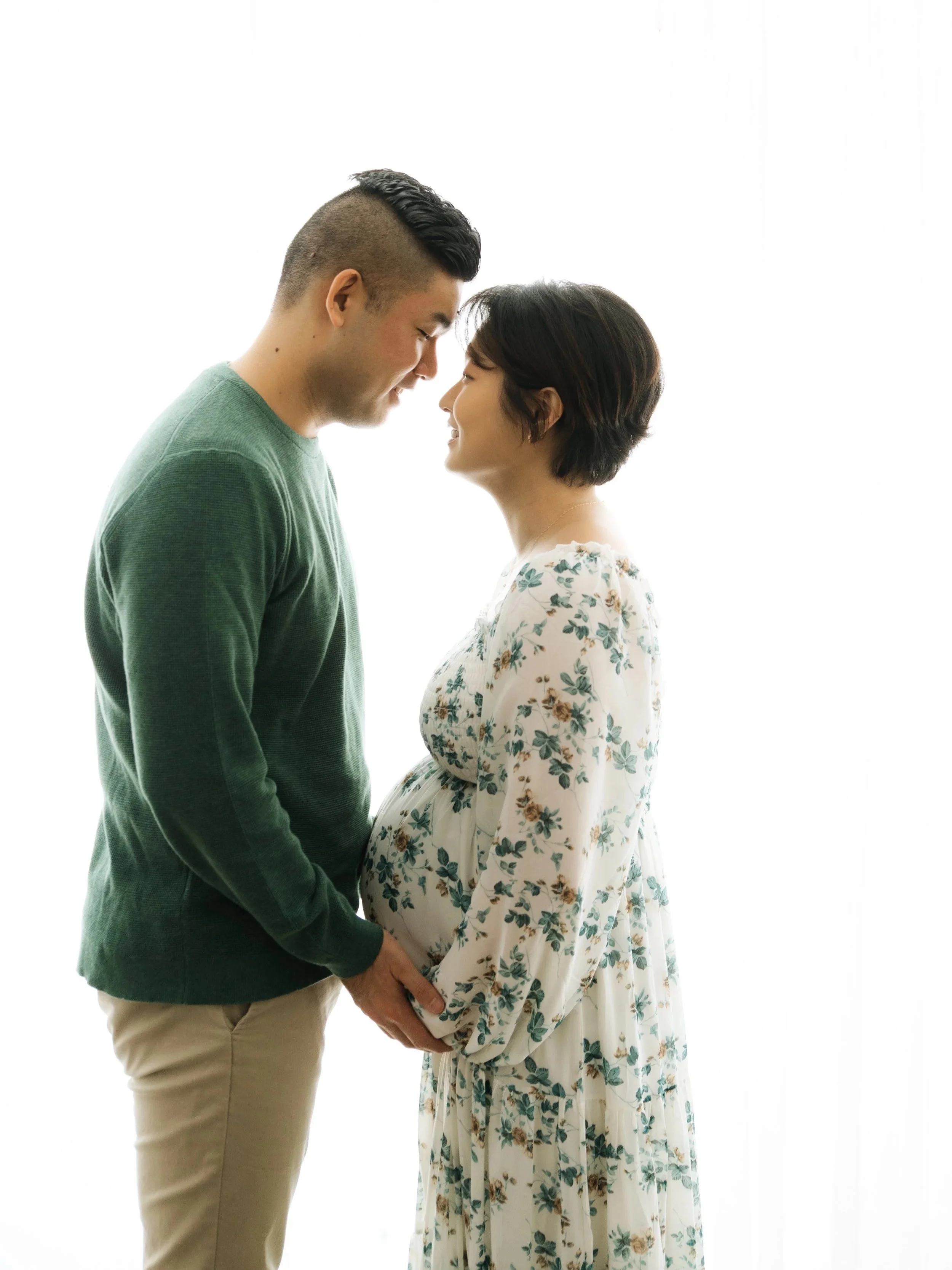 expecting couple faces each other, mom in a casual floral dress, relaxed casual maternity photoshoot, Fairfield County, ct